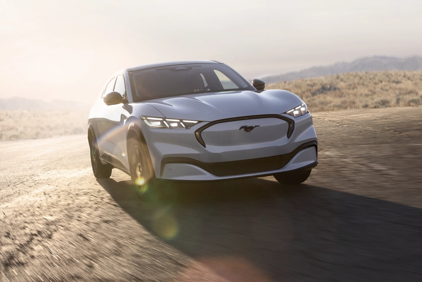 A white Mustang Mach-E® driving along a road.