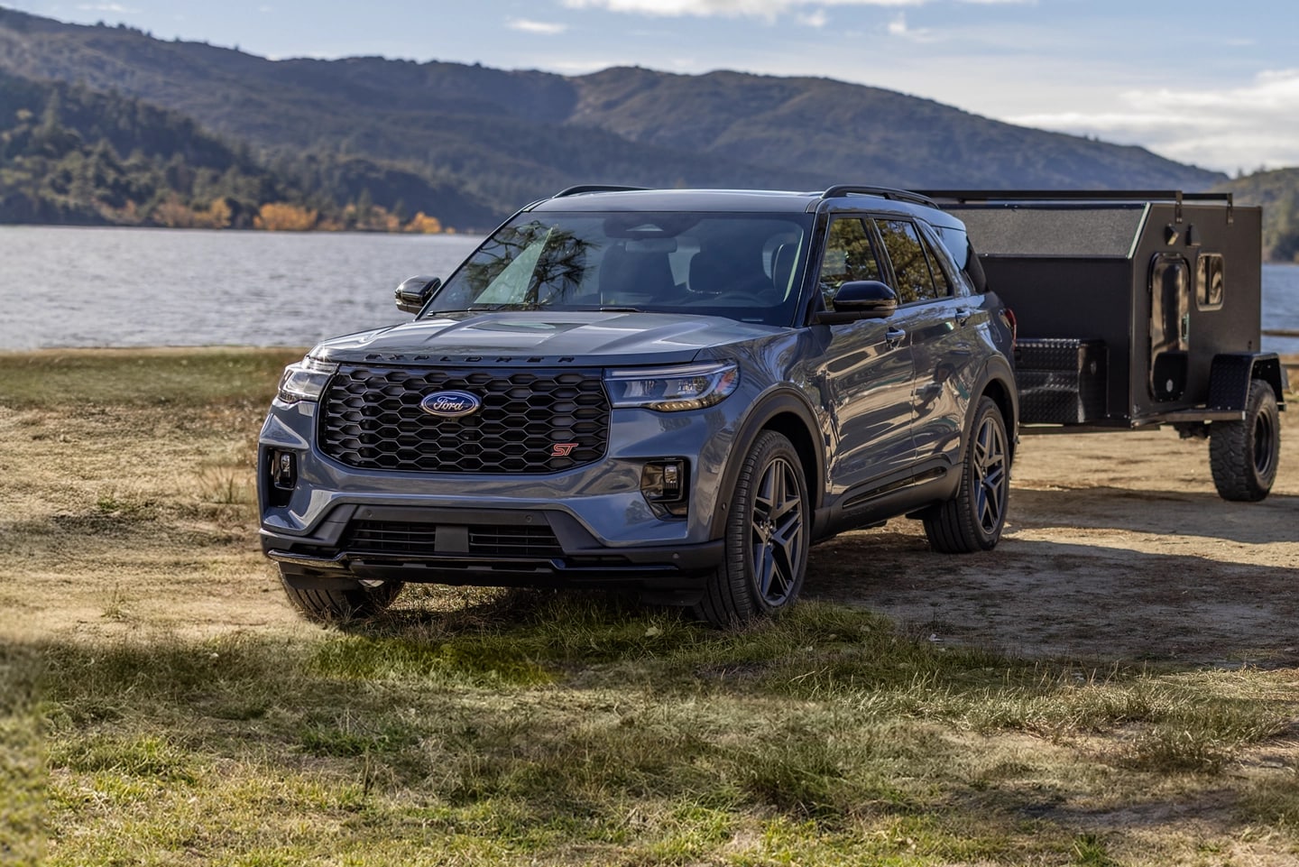 A grey Ford Explorer® parked by a lake with a trailer attached to the trunk.