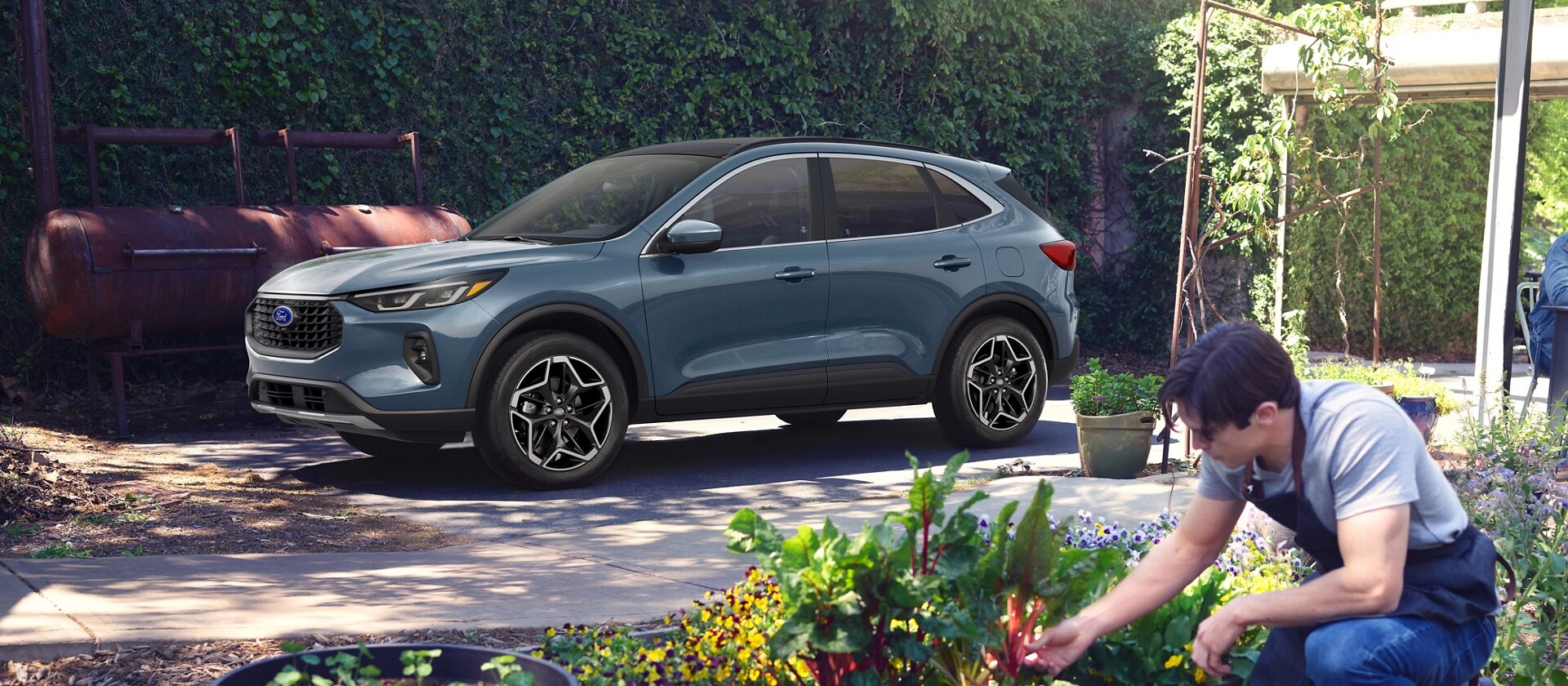 2026 Ford Escape® Platinum™ model parked in a driveway behind a person gardening