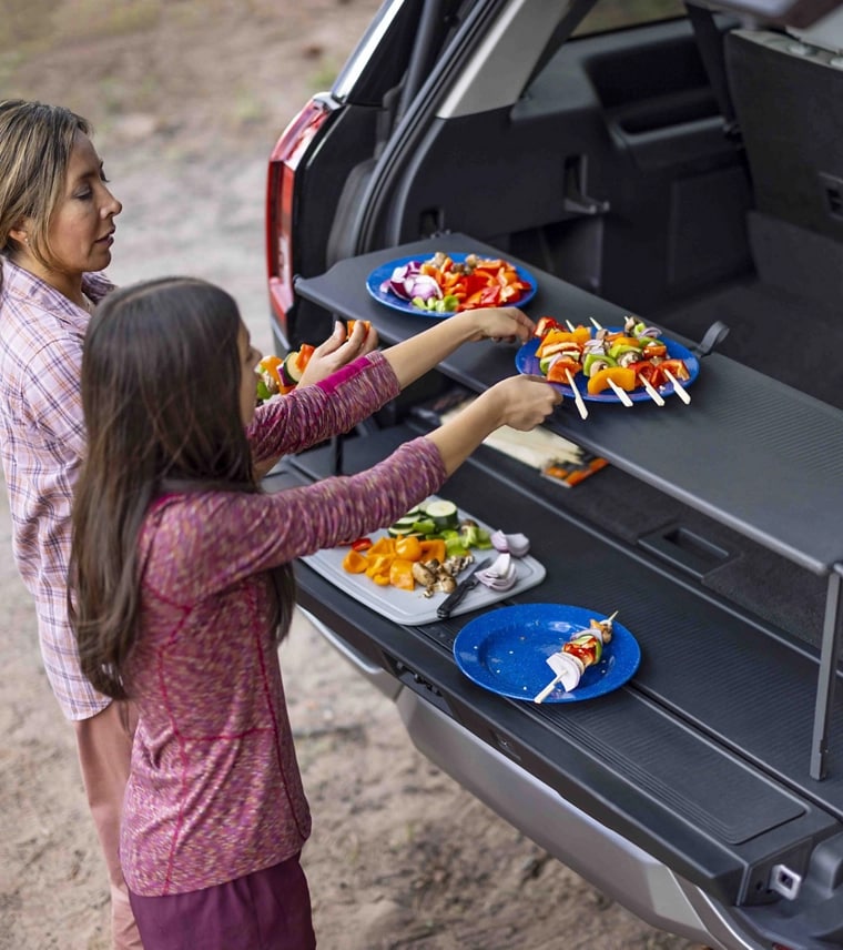 Two people using the Cargo Tailgate Manager shelf in a parked 2025 Ford Expedition® SUV