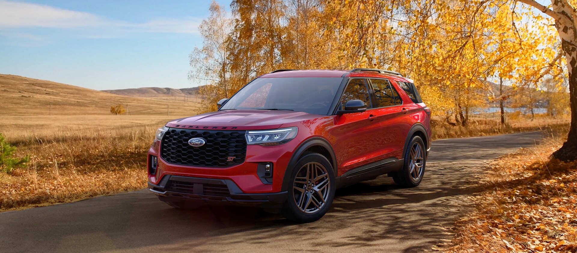 A 2026 Ford Explorer® SUV on a road through a field in the fall