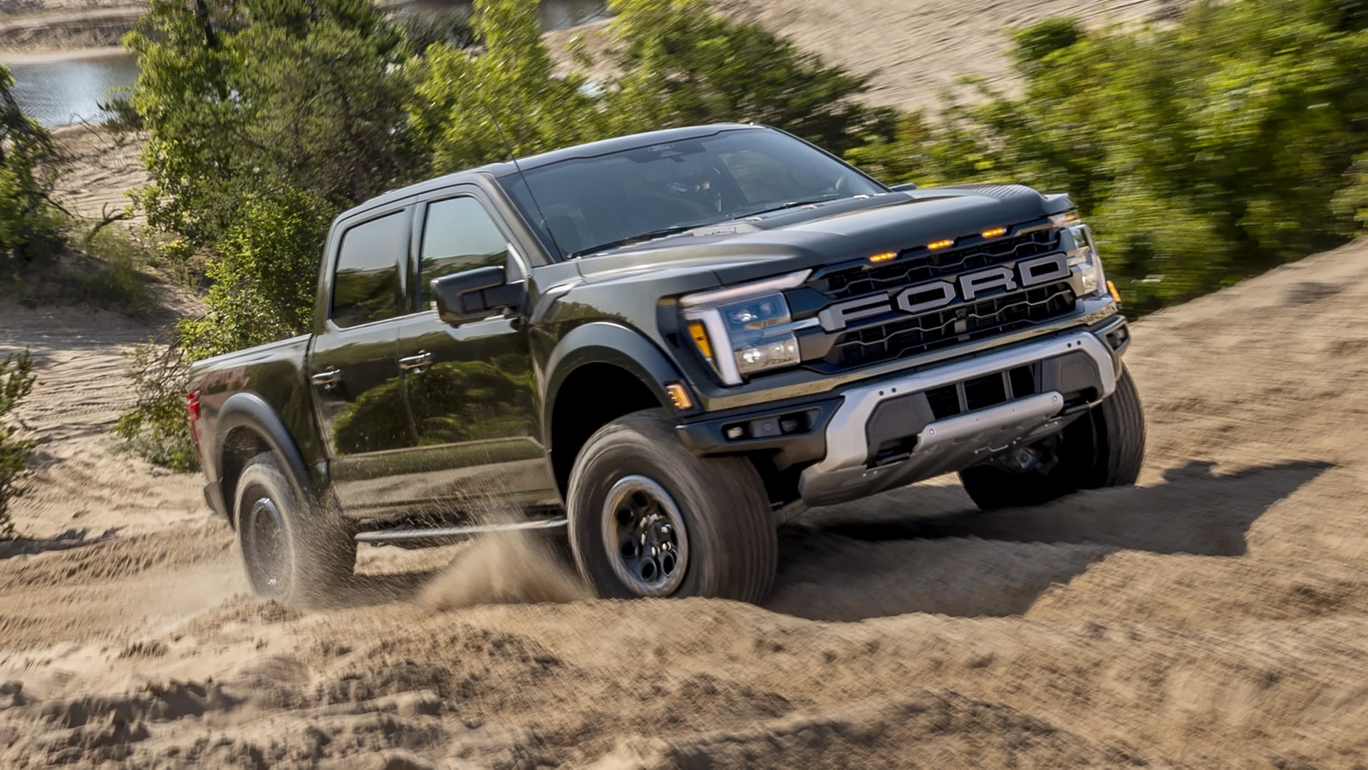2025 Ford F-150® Raptor® pickup in Shelter Green Metallic being driven on a rocky desert path