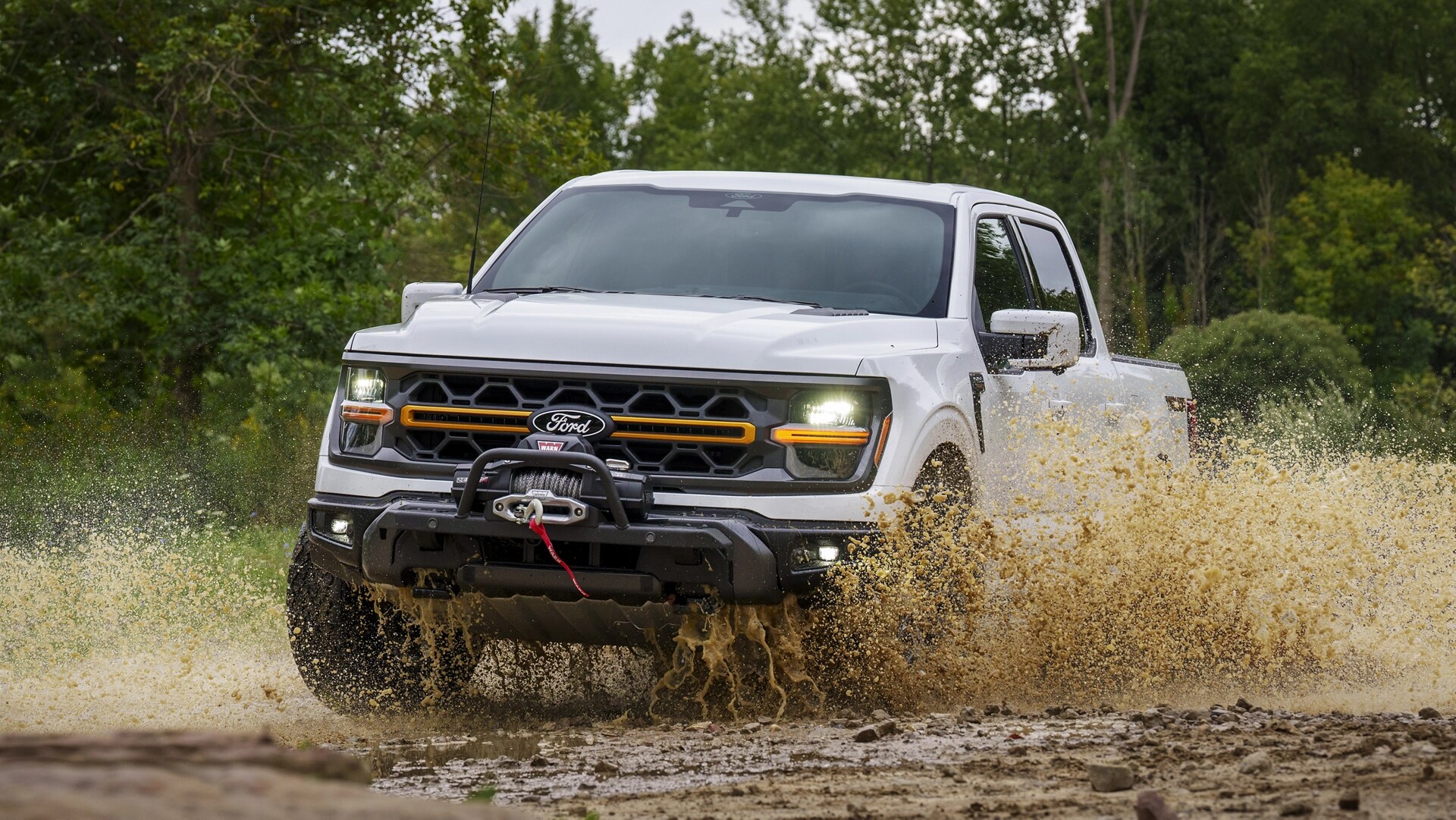 2025 Ford F-150® Tremor® pickup in Oxford White making a splash as it's being driven through a mud puddle