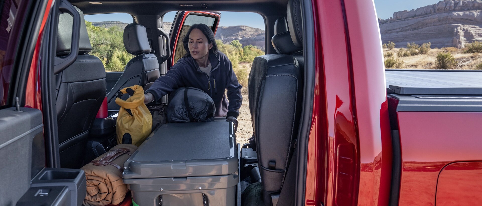 Person loading items into the rear seating area of a 2025 Ford F-150® truck with the seats folded up 
