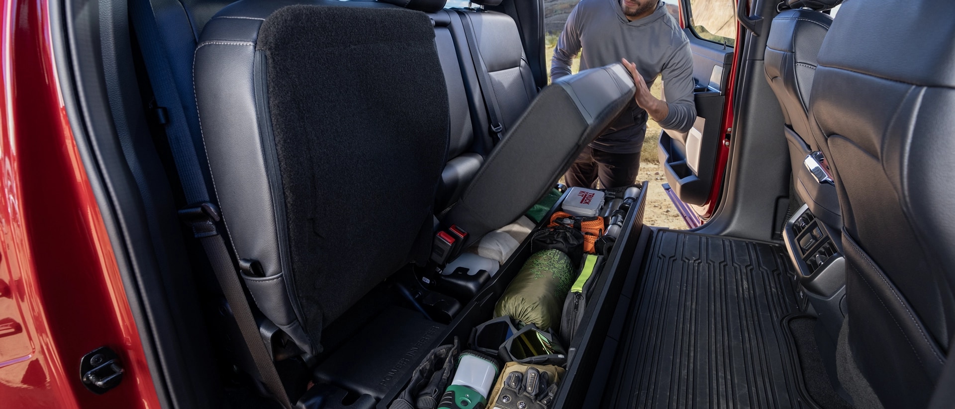Person flipping up the rear seat showing the under-seat storage feature
