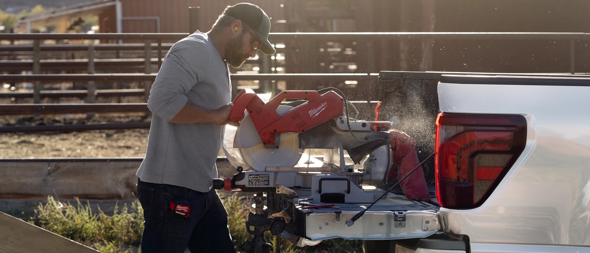 Person using a miter saw on a 2025 Ford F-150® truck tailgate while plugged into the Pro Power Onboard™ feature