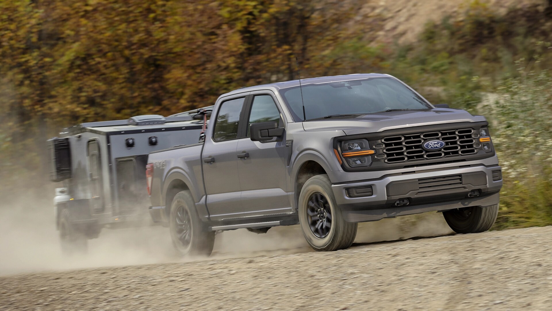 2025 Ford F-150® FX4® model pulling a small camper on a dirt road