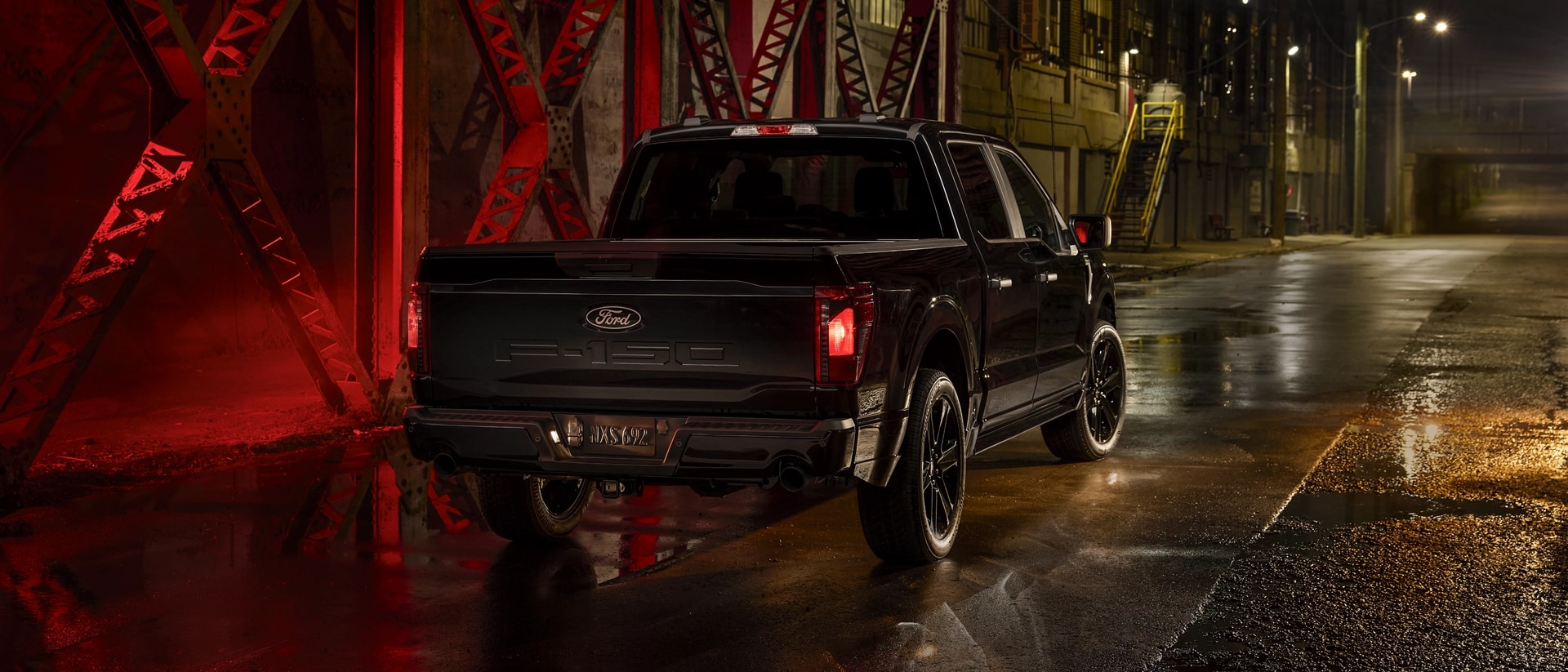 The rear view of a black 2025 F-150® STX with Lobo™ Package truck parked on a vacant city street at night