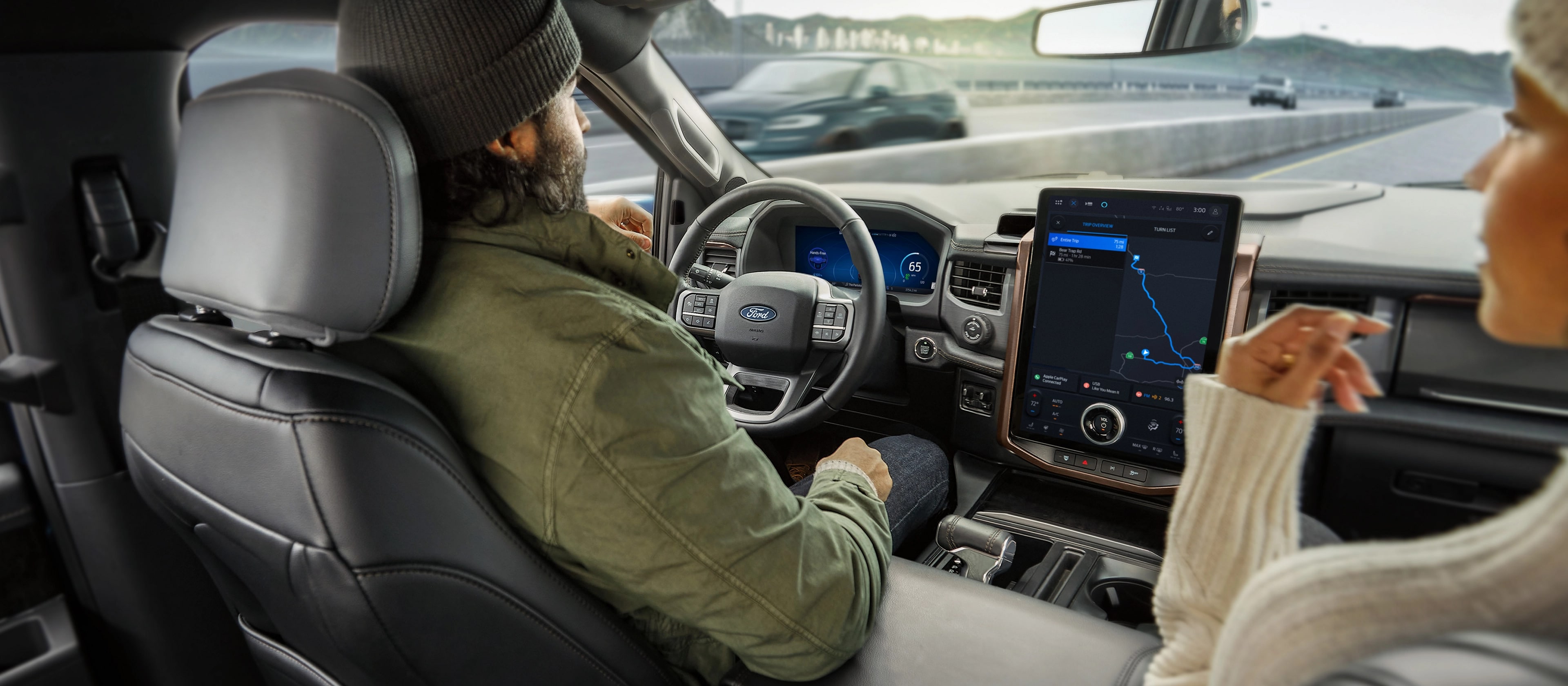 Two people in a 2025 Ford F-150® Lightning® driving down the highway, using the BlueCruise feature