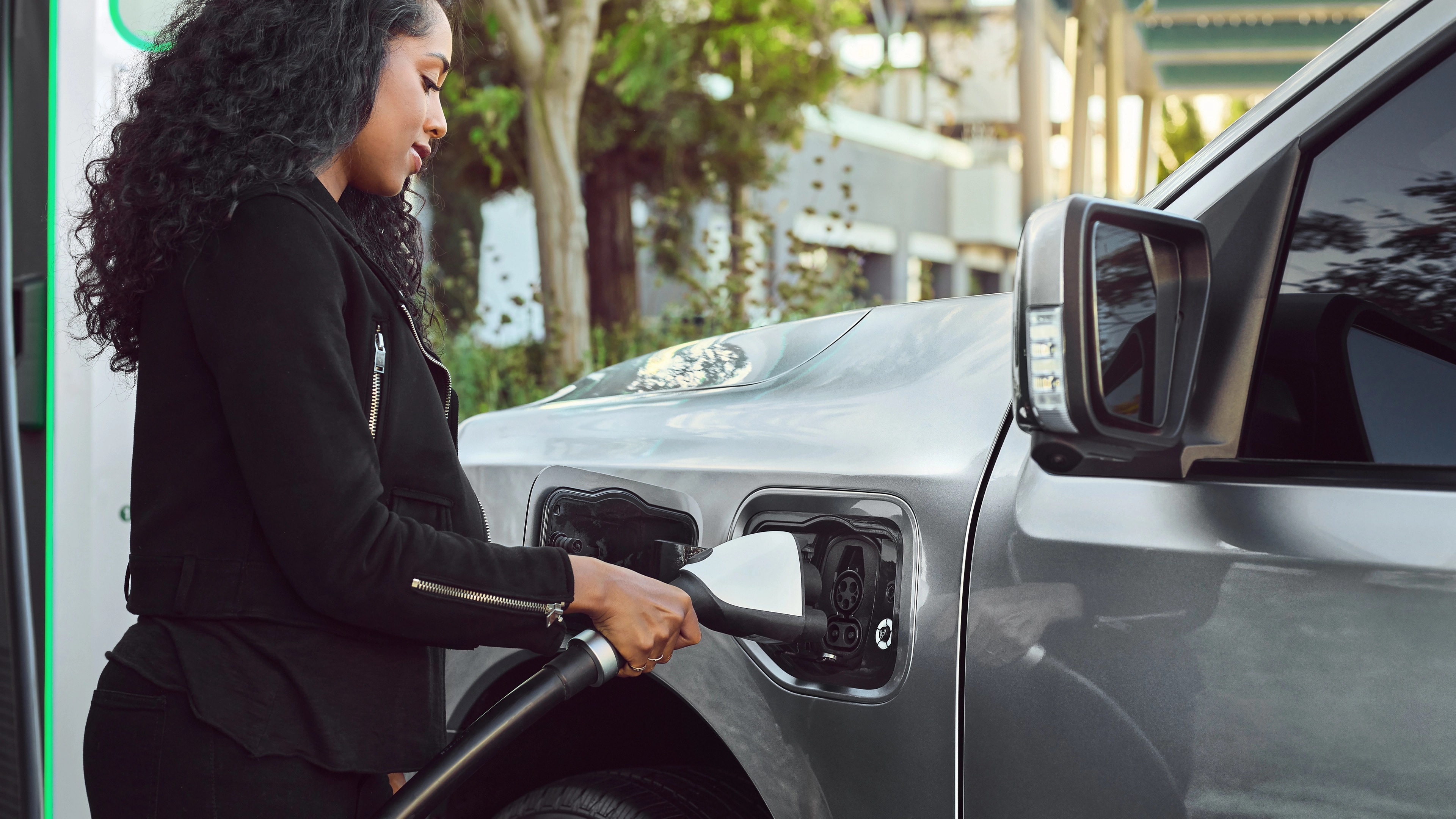 A woman plugging a charger into the charge port on a 2025 Ford F-150® Lightning® pickup