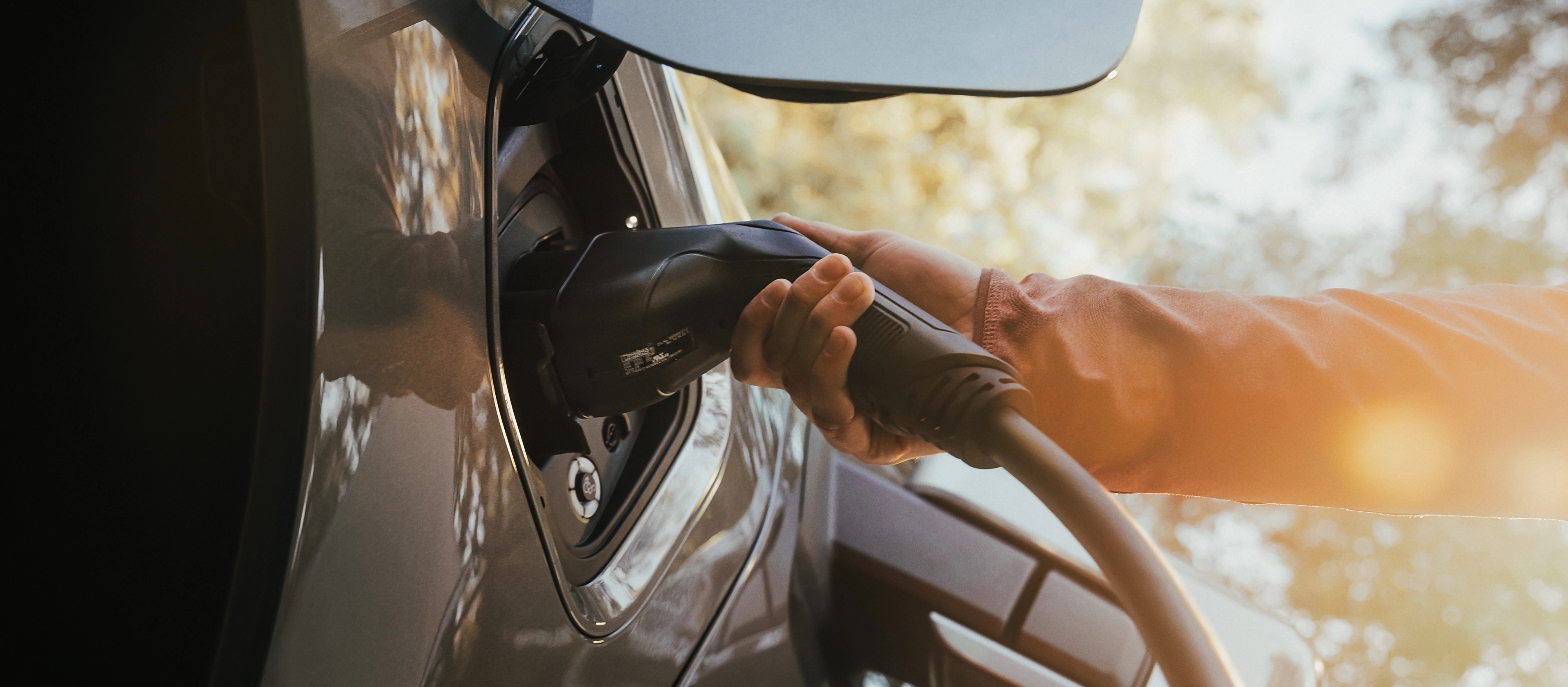 The charge port on a 2025 Ford F-150® Lightning® pickup, with a hand holding the charger plug