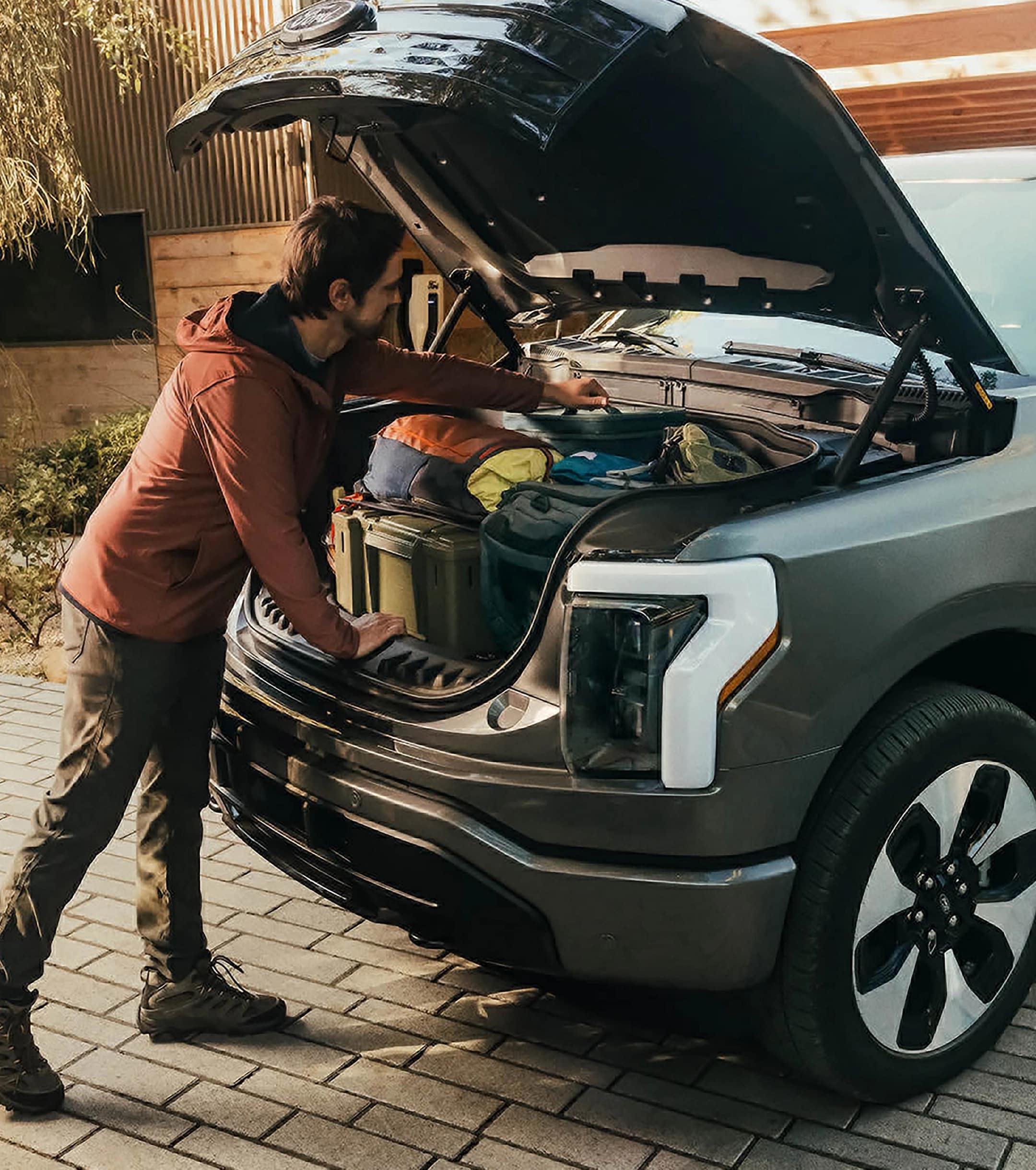 A person reaching into the Mega Power Frunk on a 2025 Ford F-150 Lightning® pickup filled with boxes and bags