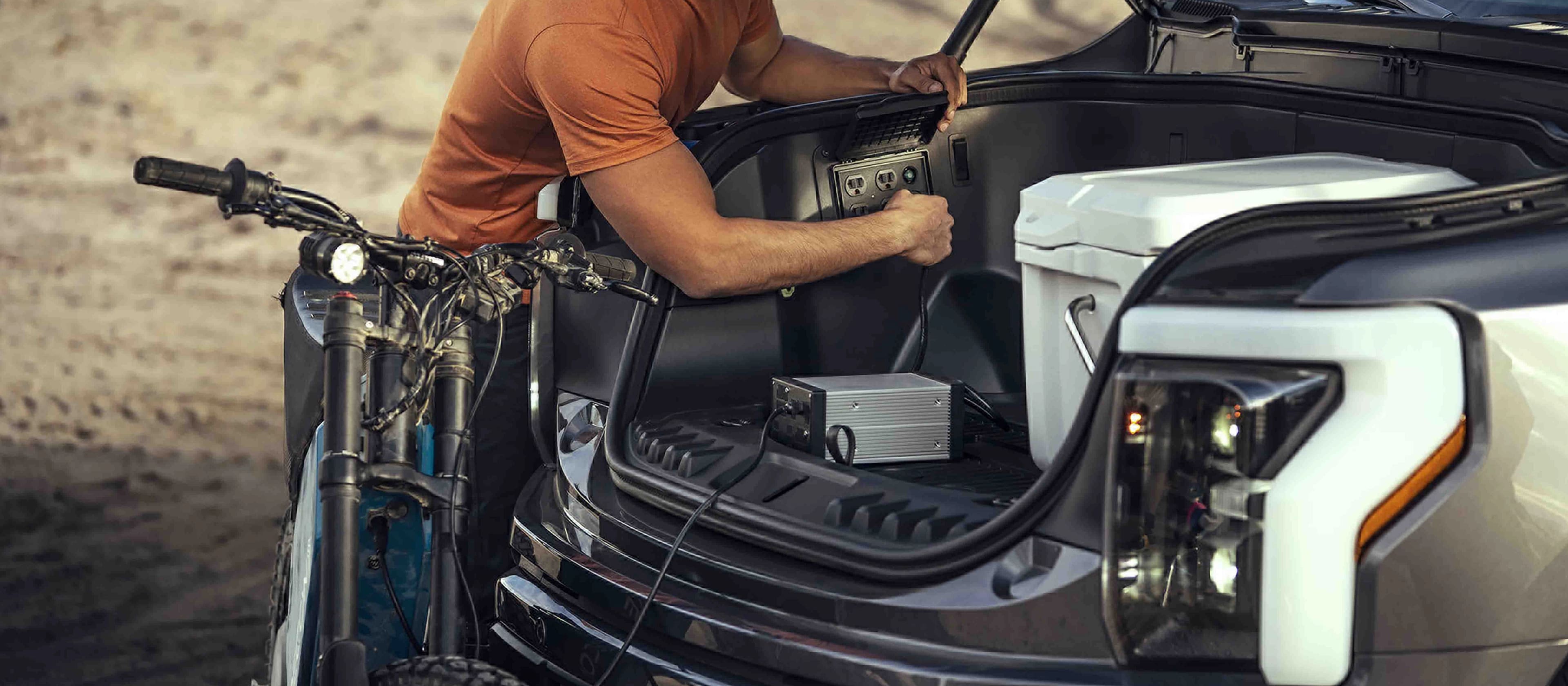 A person plugging an electric dirtbike into the Pro Power Onboard™ outlet on a 2025 Ford F-150® Lightning® pickup