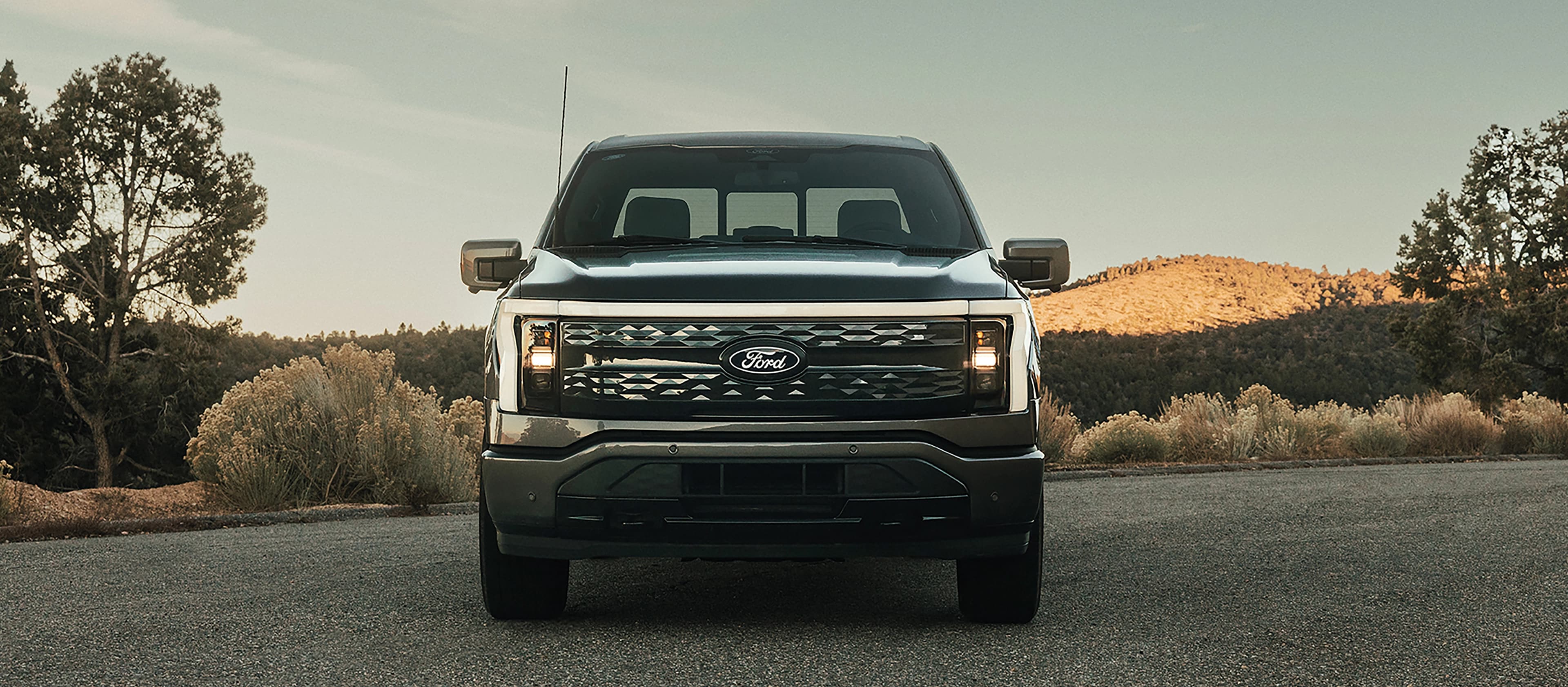 A 2025 Ford F-150® Lightning® is head on parked at sunset in a scenic location