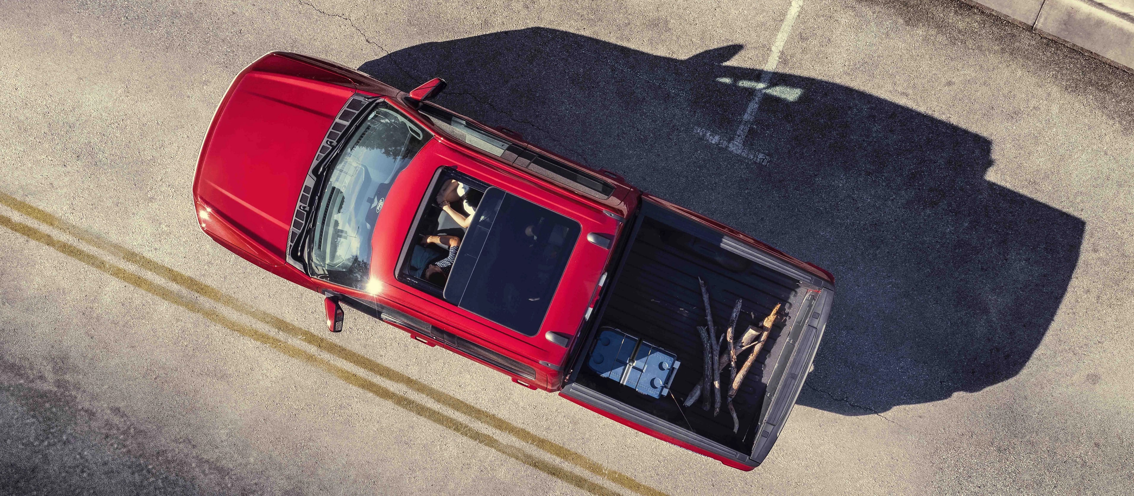 An aerial view of two people in a 2025 Ford F-150® Lightning® featuring the sunroof and cargo in the truck bed