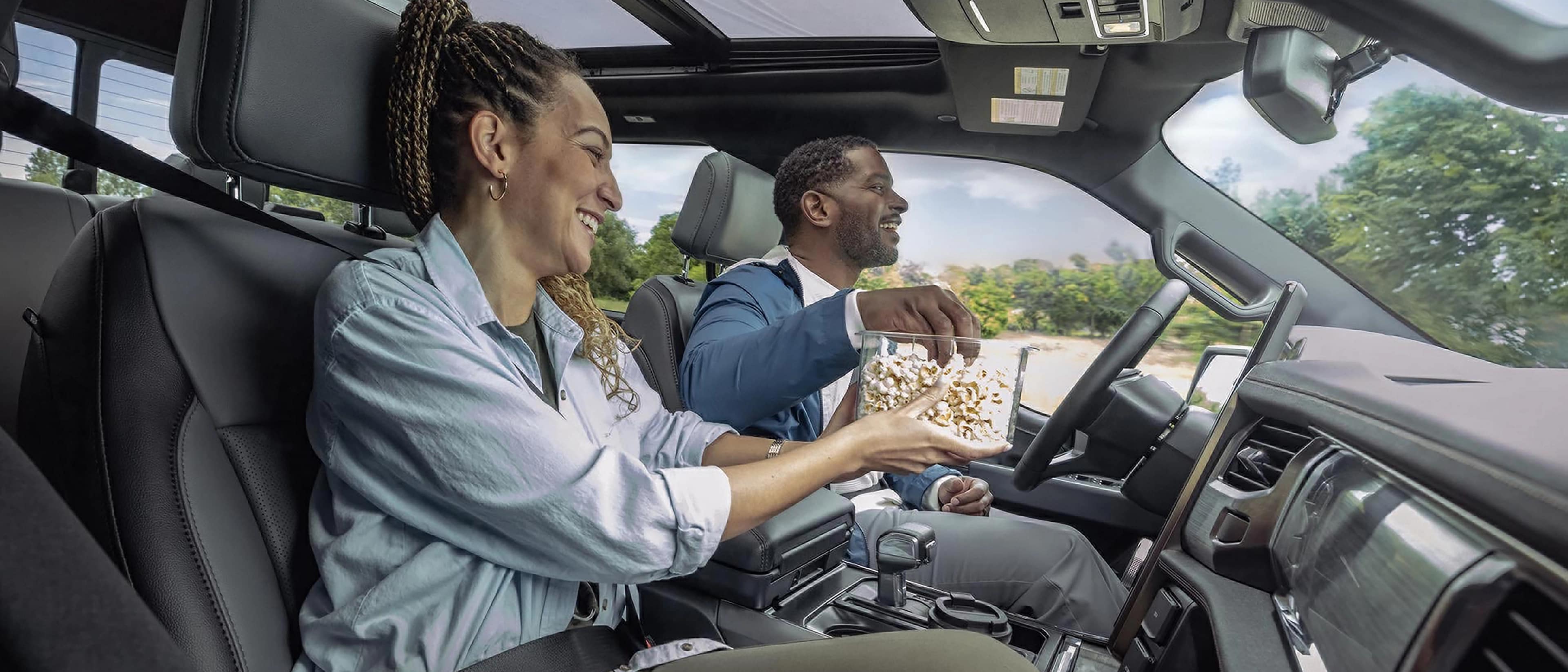 A driver and passenger eating popcorn in a 2025 Ford F-150® Lightning® engaged with the BlueCruise feature