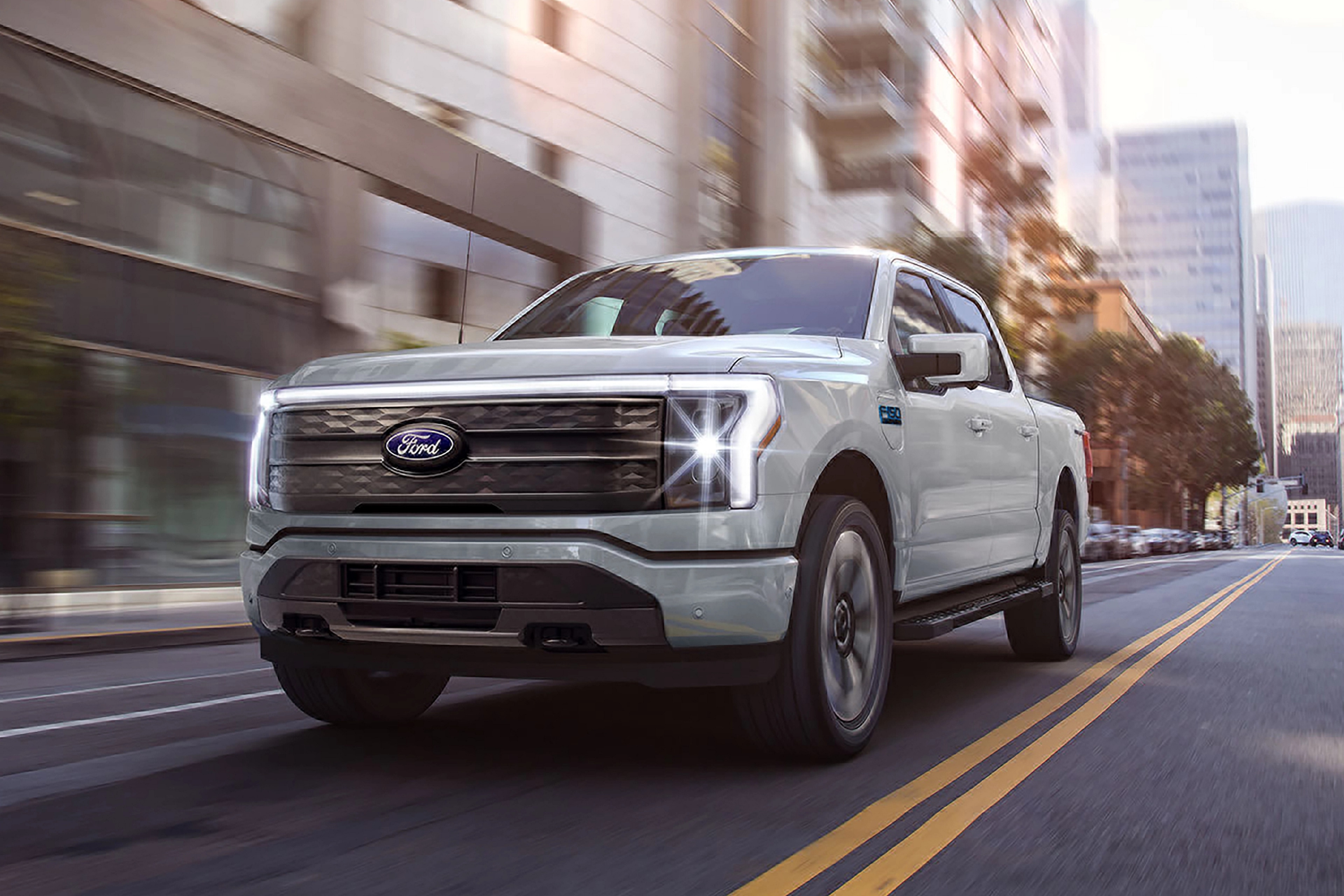 A 2025 Ford F-150® Lightning® pickup being driven down a city street
