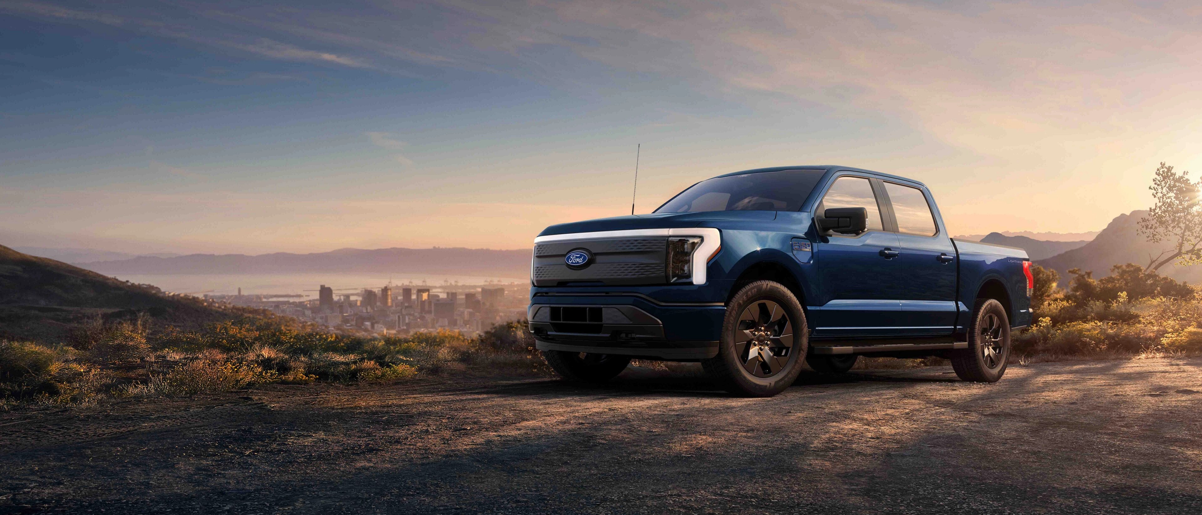 A 2025 Ford F-150® Lightning® pickup parked on a hilltop overlooking the Long Beach, California skyline