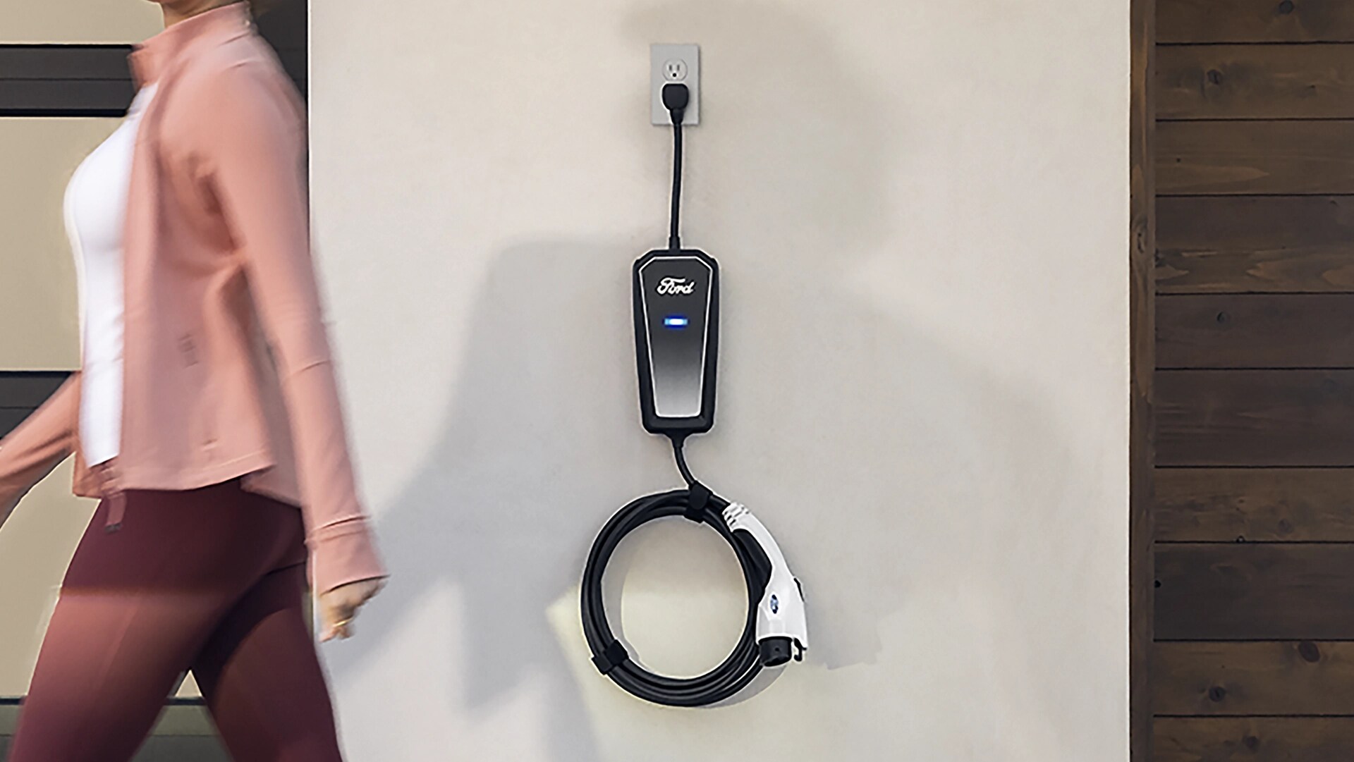 Woman walking by a Ford Mobile Power Cord installed on a wall