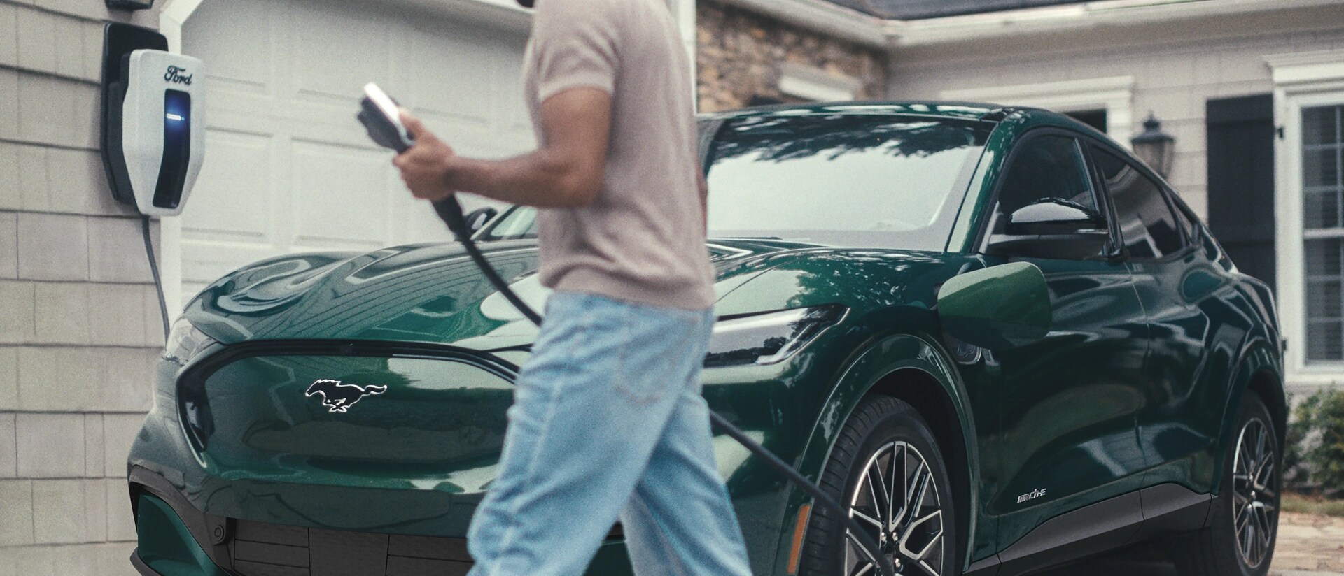 Man plugs in a 2025 Ford Mustang Mach-E® parked outside a home