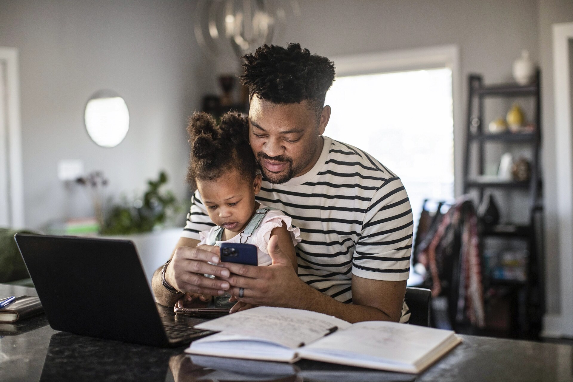 A man holds his child in his lap while interacting with the FordPass app on his phone