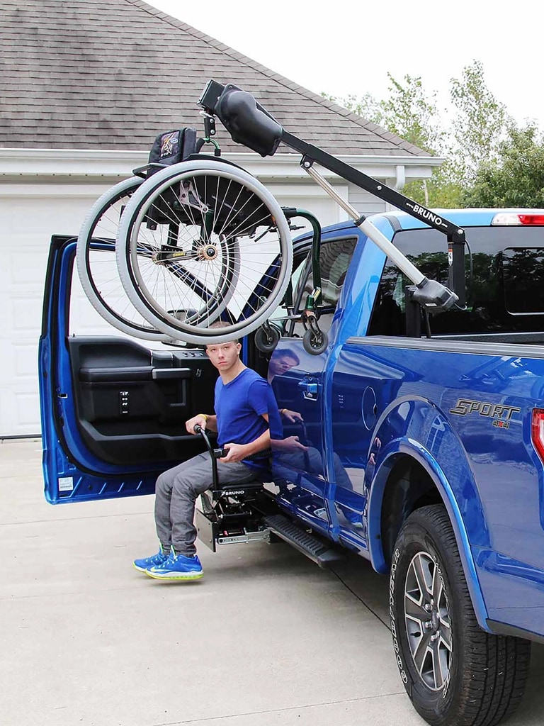 A blue F-150 with a wheelchair hoist in the bed