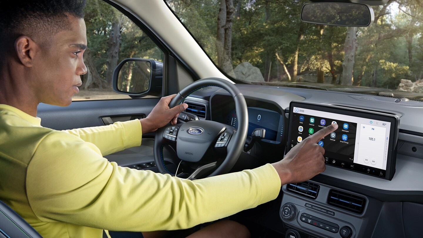 A driver using the touchscreen on a parked 2025 Ford Maverick® pickup