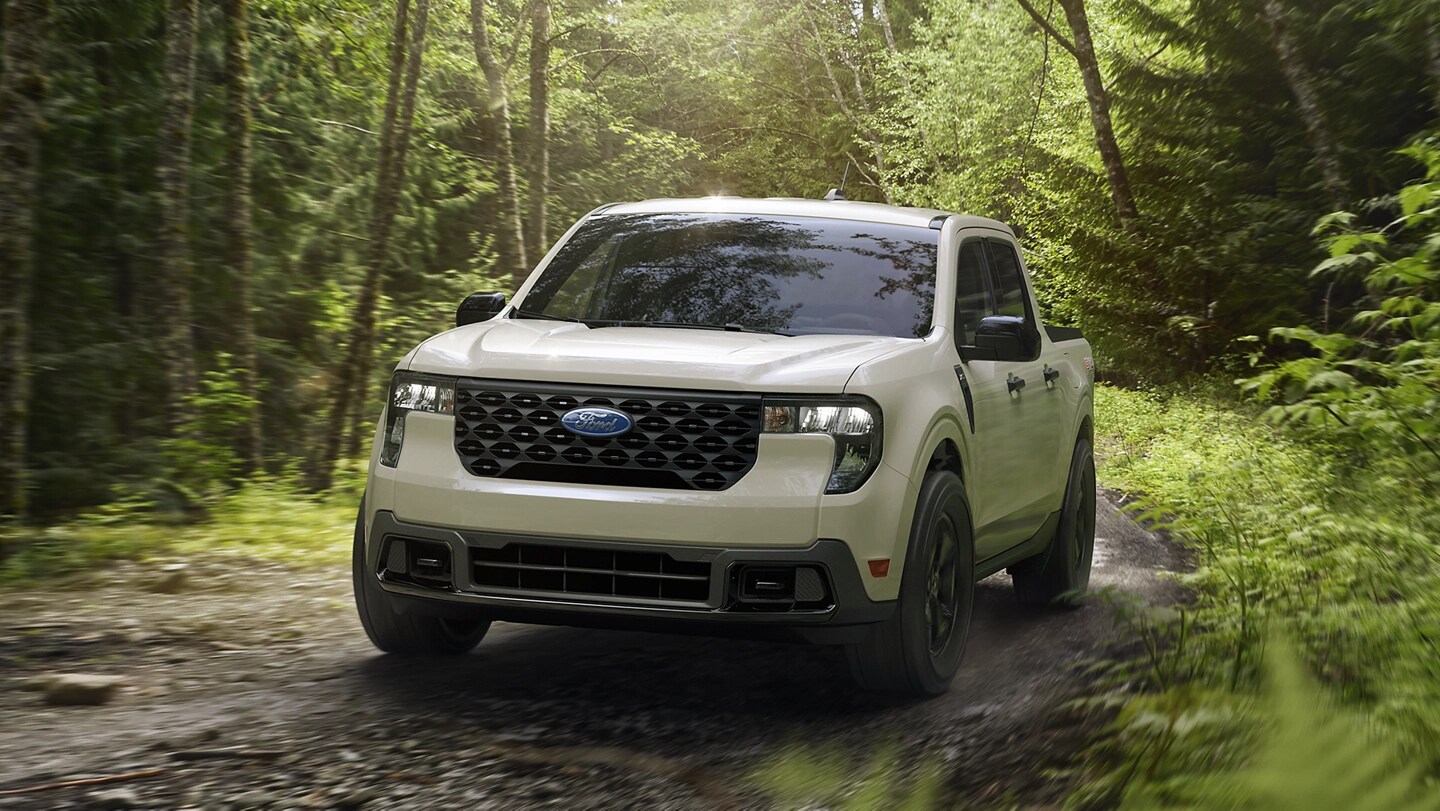 A 2025 Ford Maverick® XLT pickup with FX4® Off-Road Package driving on a muddy forest trail