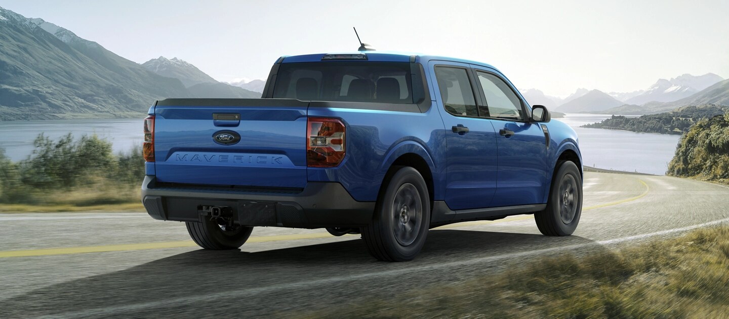 A 2025 Ford Maverick® pickup driving toward a mountain lake in the afternoon