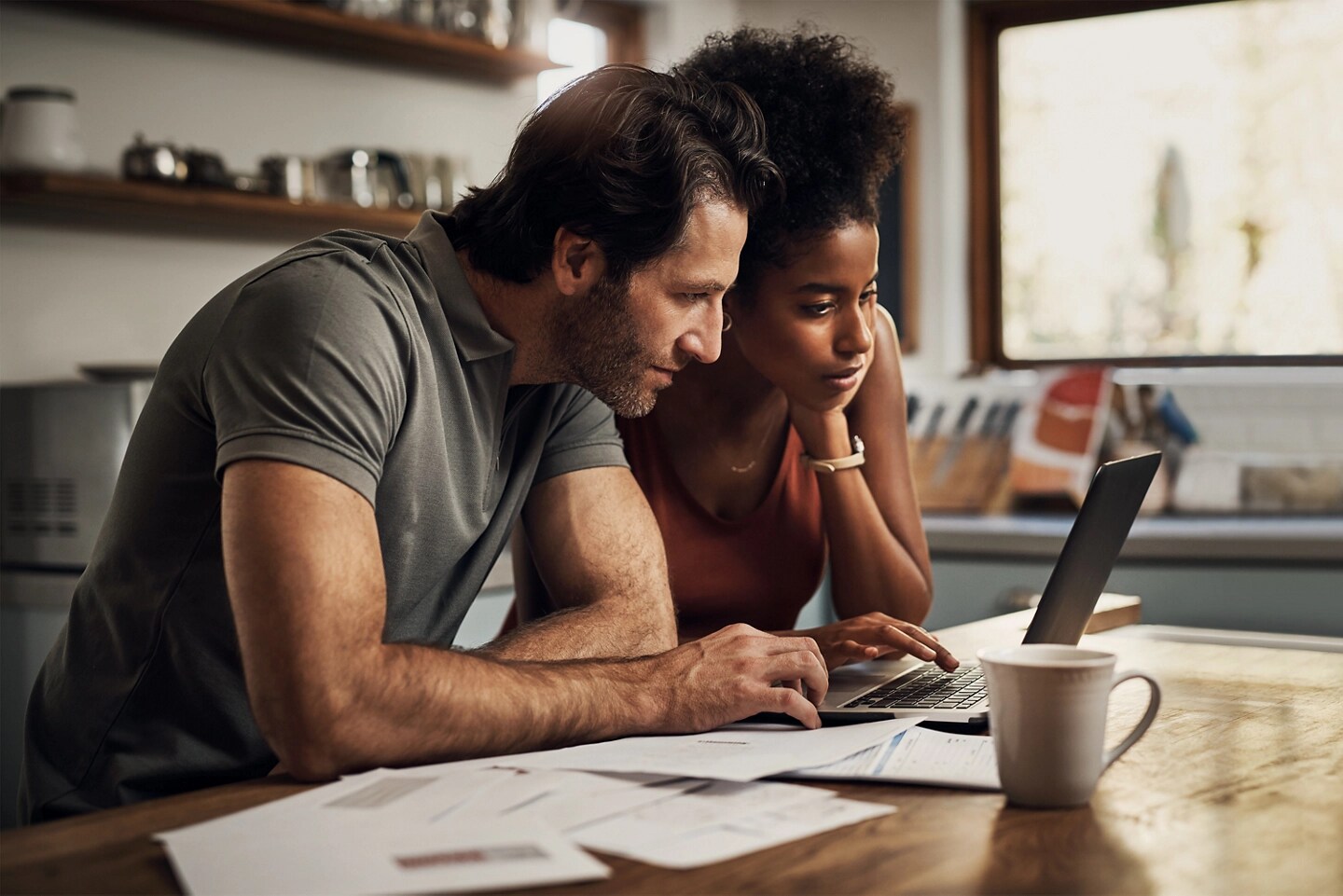 A couple looking at a laptop computer in their kitchen