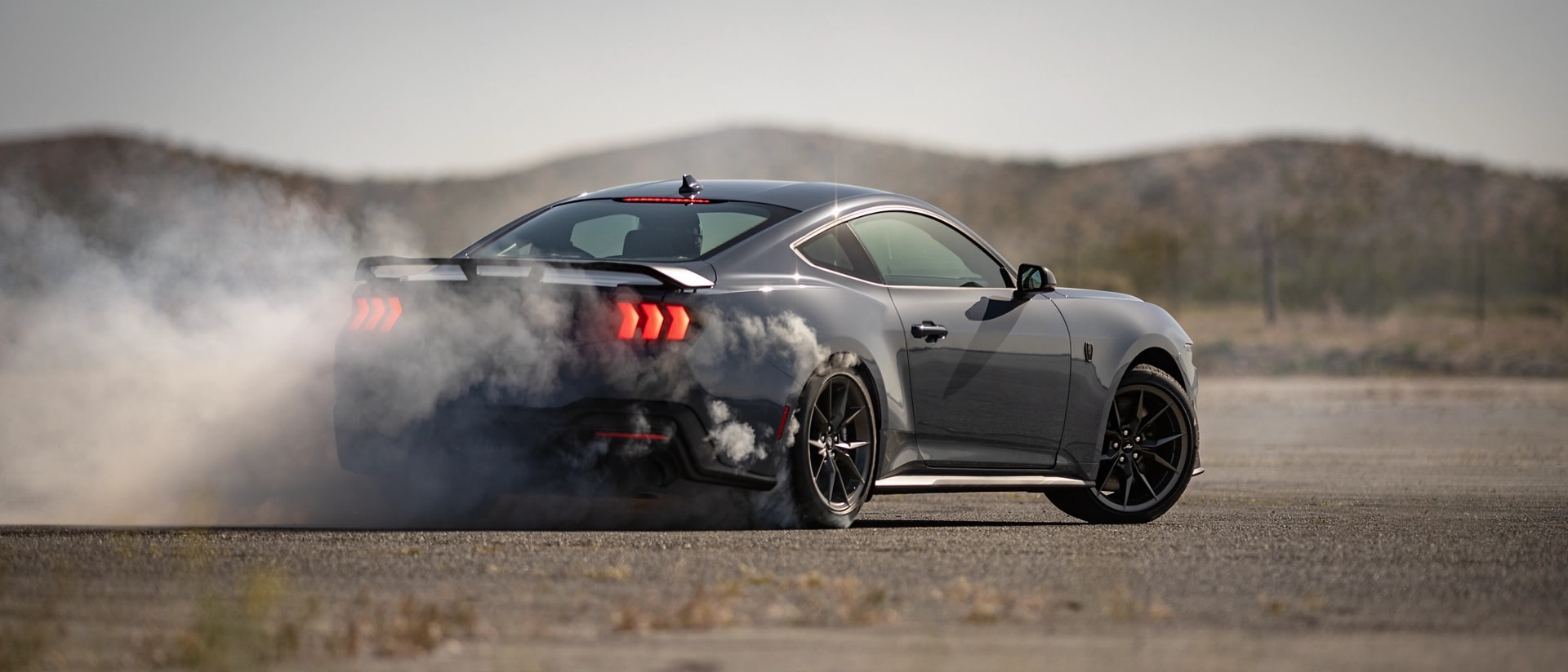 2025 Ford Mustang® Dark Horse™ coupe in Vapor Blue Metallic with a driver performing burnouts on a closed course