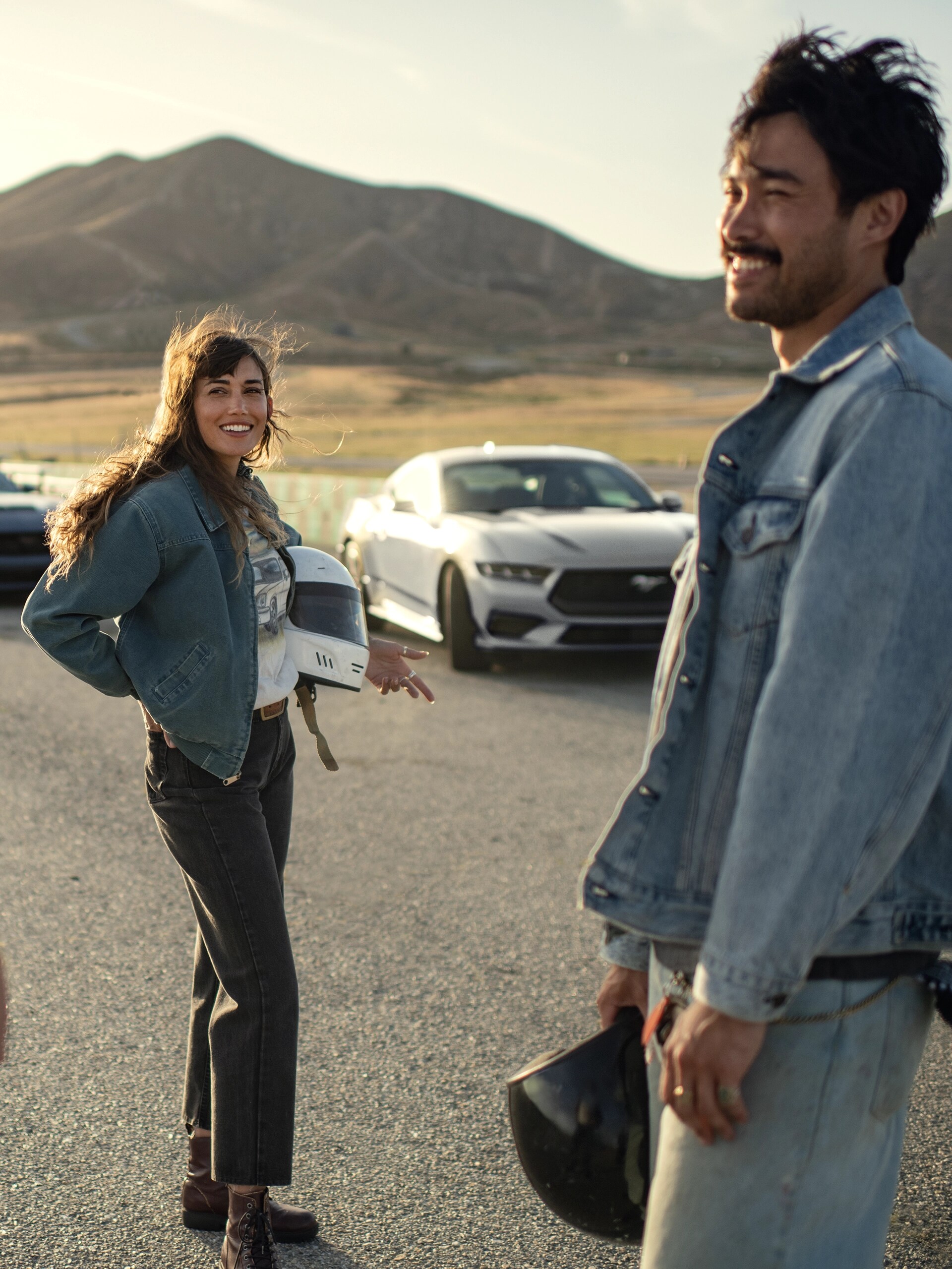 A 2025 Ford Mustang® coupe parked near a racecourse with two people nearby