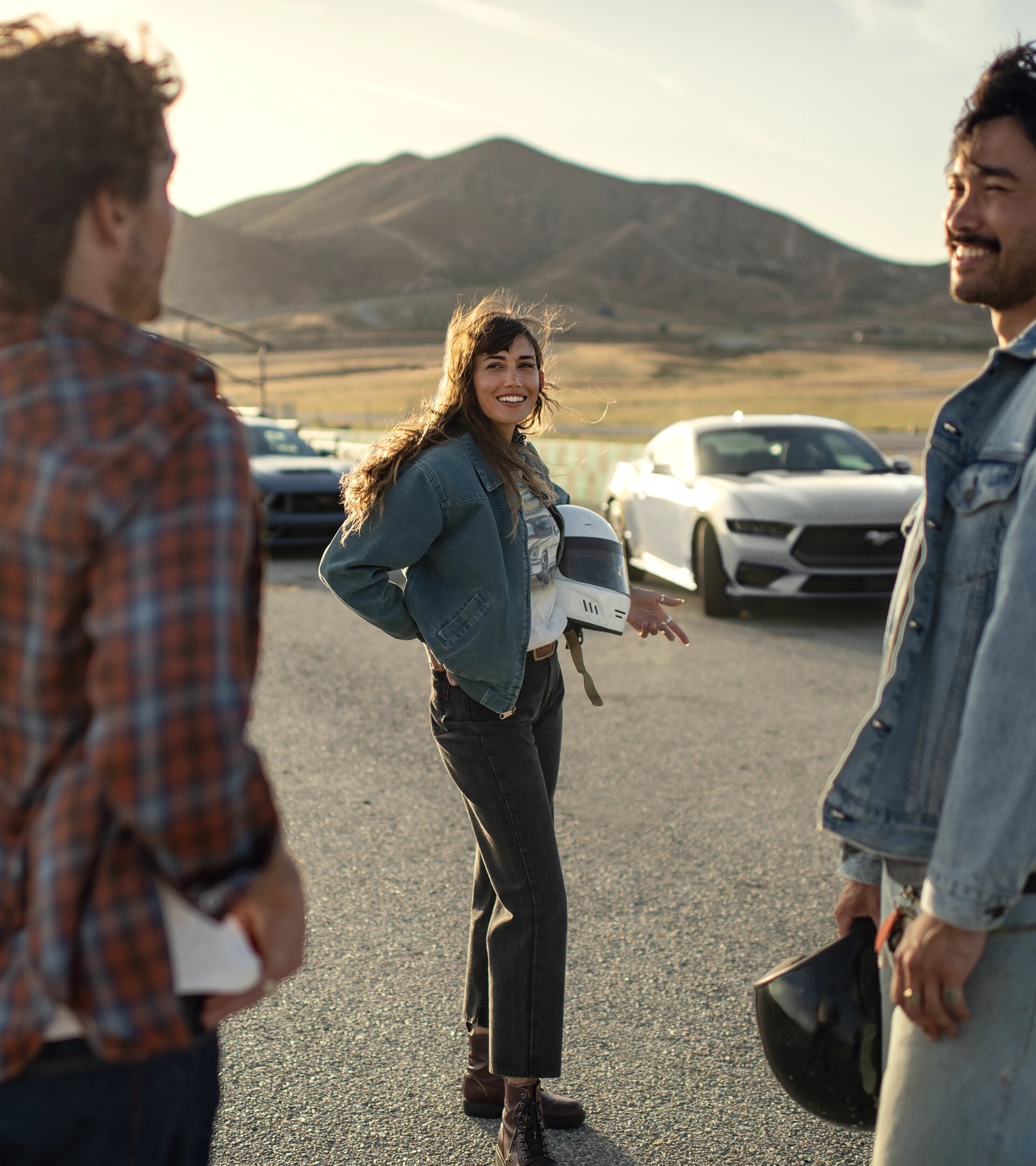 A 2026 Ford Mustang® fastback parked near a racecourse with two people nearby