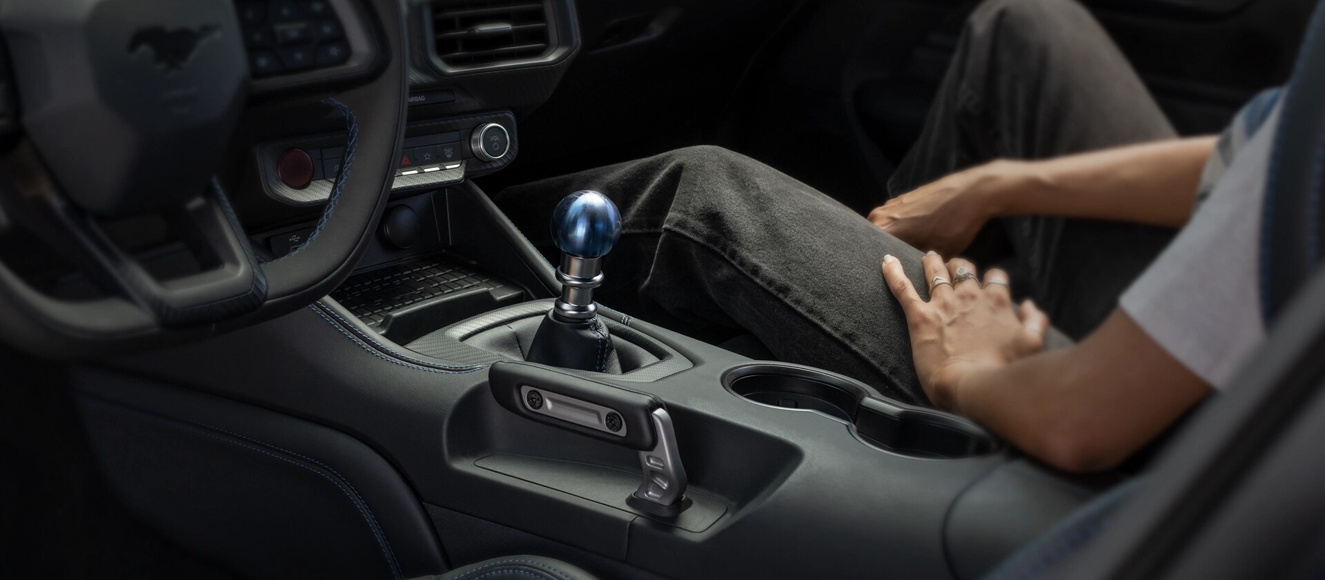 Person sitting in a 2026 Ford Mustang Dark Horse® fastback with unique titanium Anodized Blue shift knob