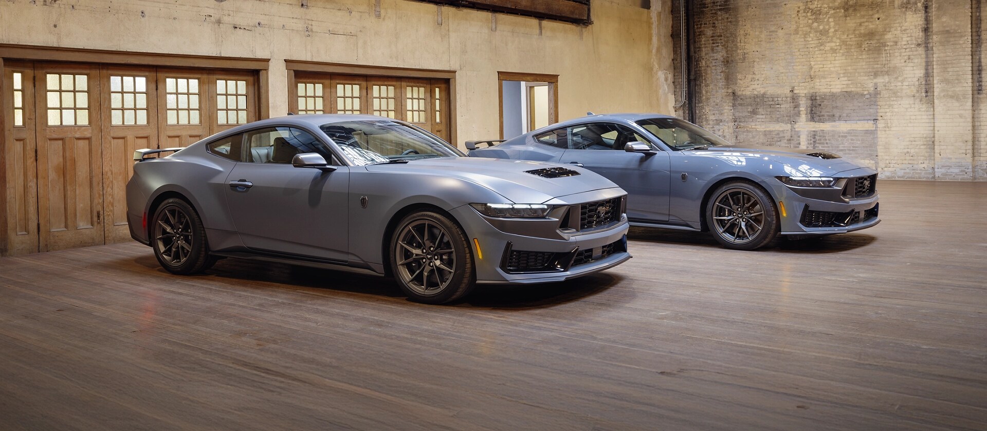 Two 2026 Ford Mustang® fastbacks parked in a garage, one with the available Matte Clear Film