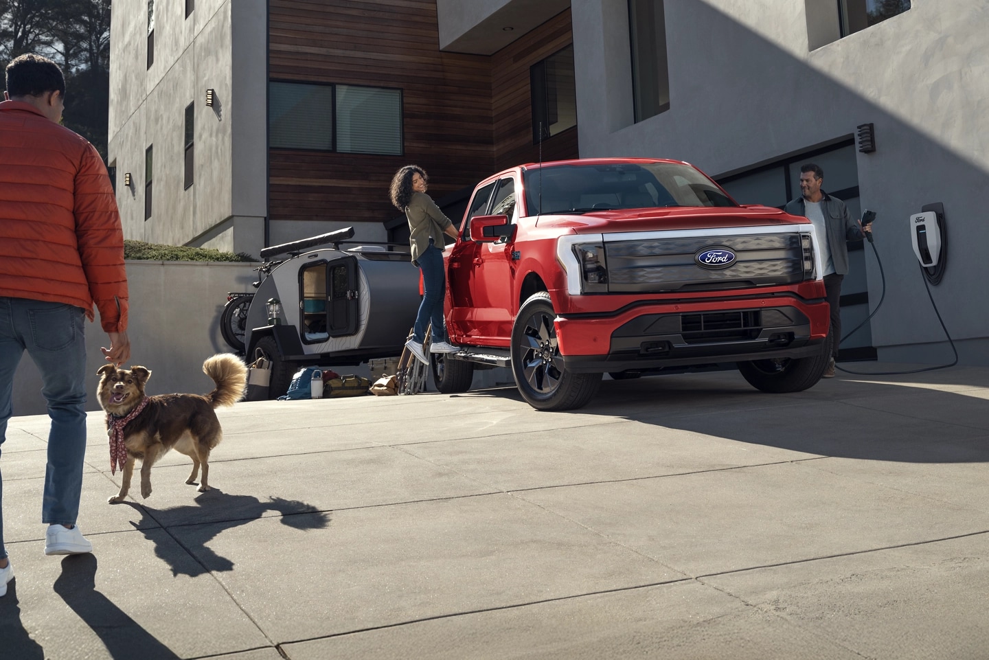 An F-150 Lightning parked in a driveway next to a Ford Charge Station Pro.