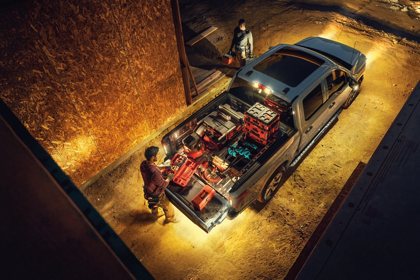 An F-150 Lightning with 360 LED lights on while a person loads equipment into the truck bed.
