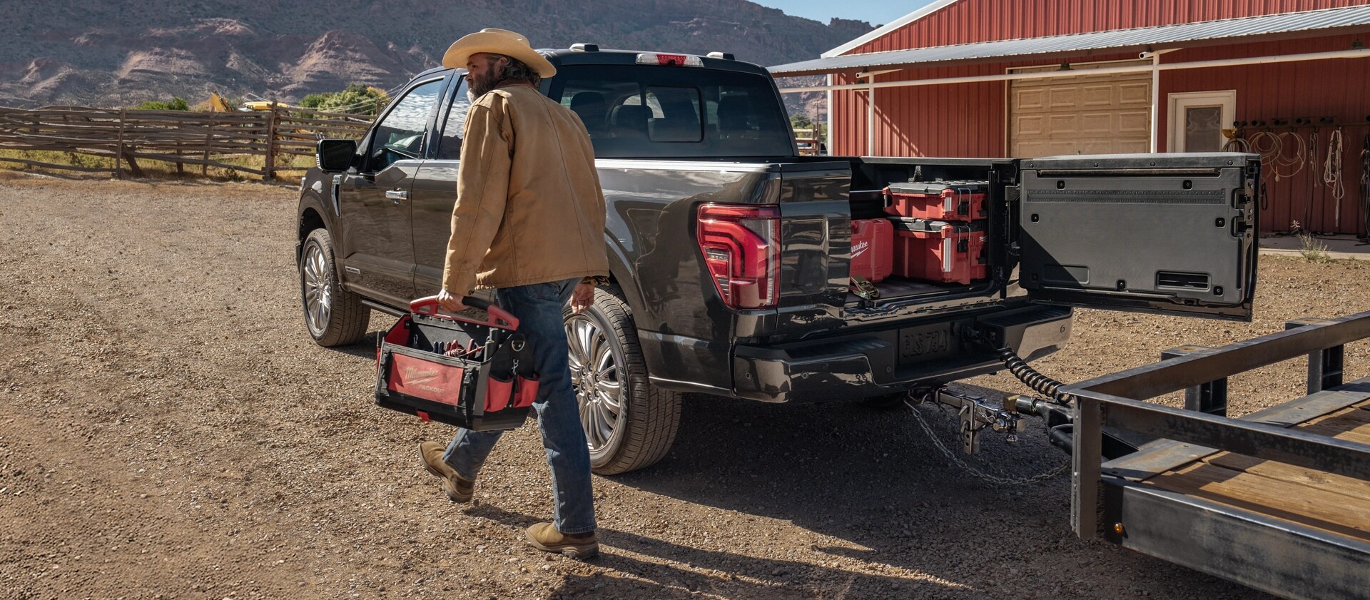 A man walks by an F-150 with a trailer hitched and Pro Access Tailgate open.