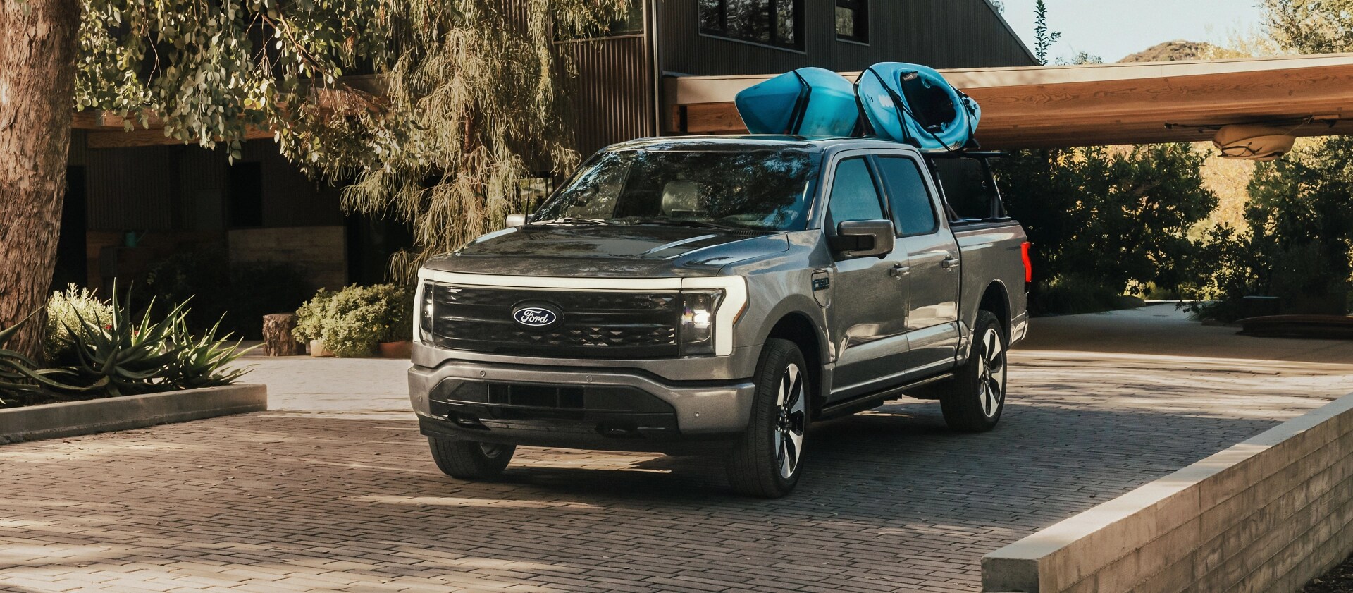 An F-150 Lightning with kayaks strapped to a rear-mounted rack.