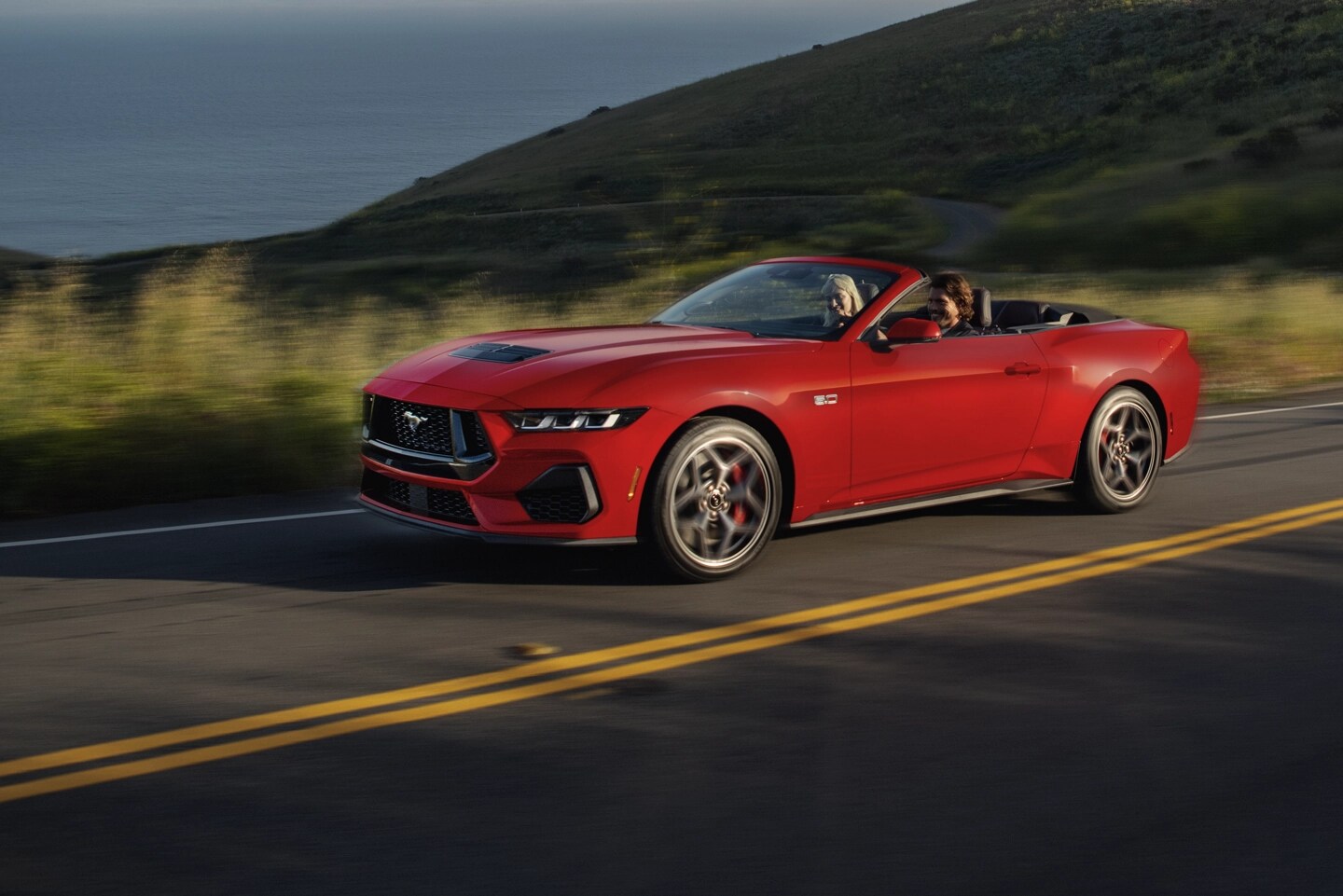 Mustang convertible driving on a two-lane highway.