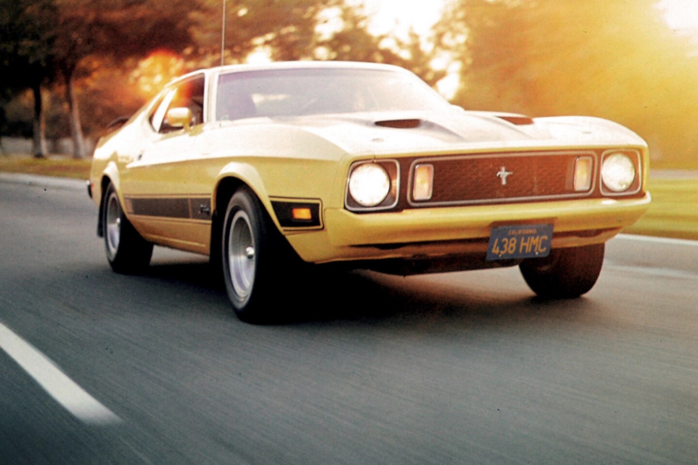 Vintage Mustang driving on a suburban road.