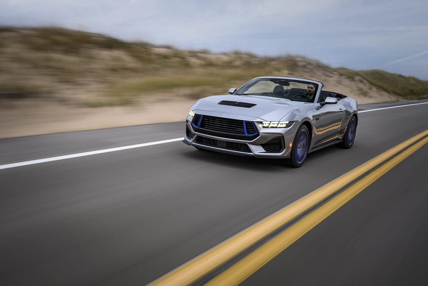 Mustang convertible driving on a two-lane highway.