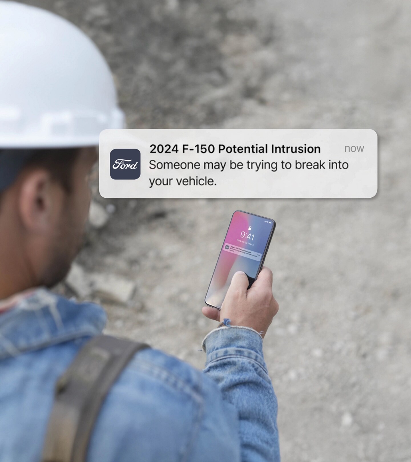 Person holding a smartphone displaying a notification. Overlay of text that reads: Potential intrusion! Someone may be trying to break into your vehicle.