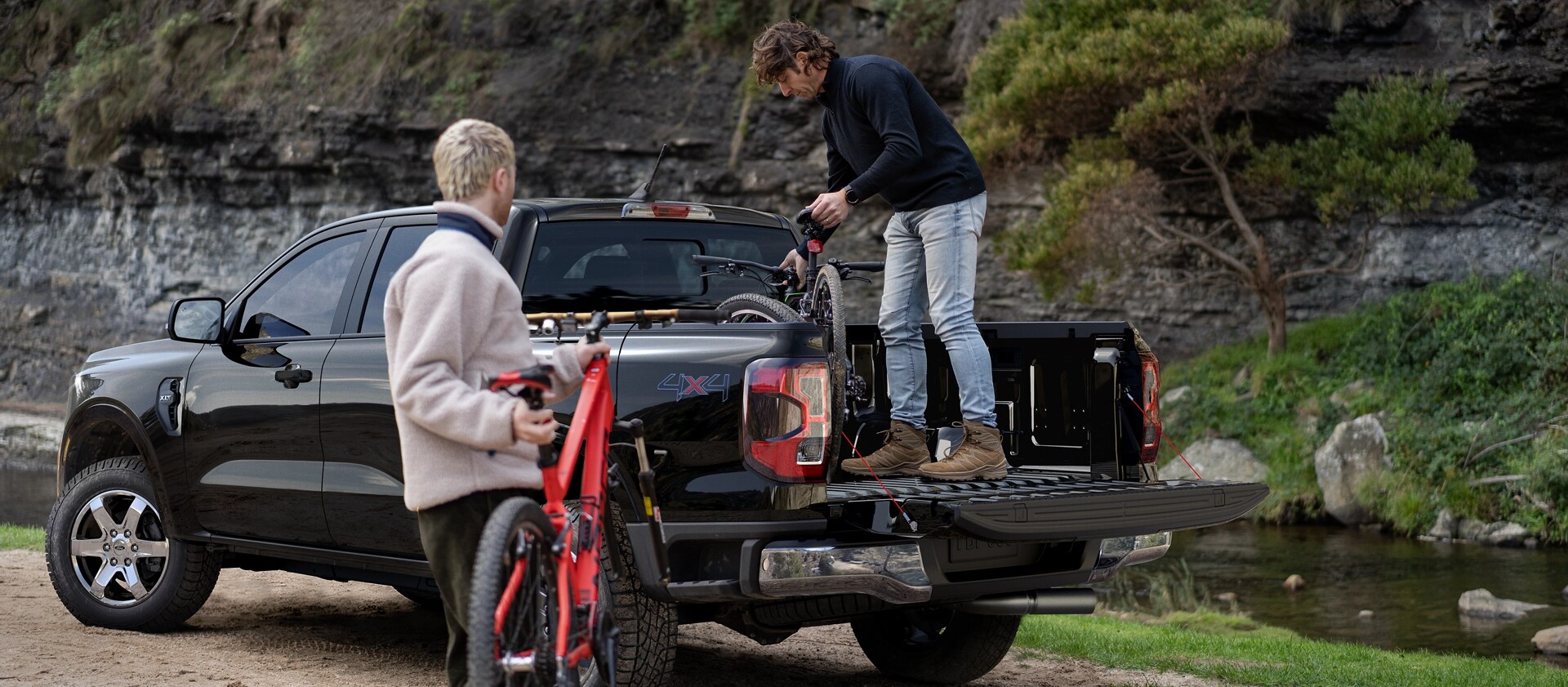 Two people loading gear into the bed of a black 2025 Ford Ranger® pickup