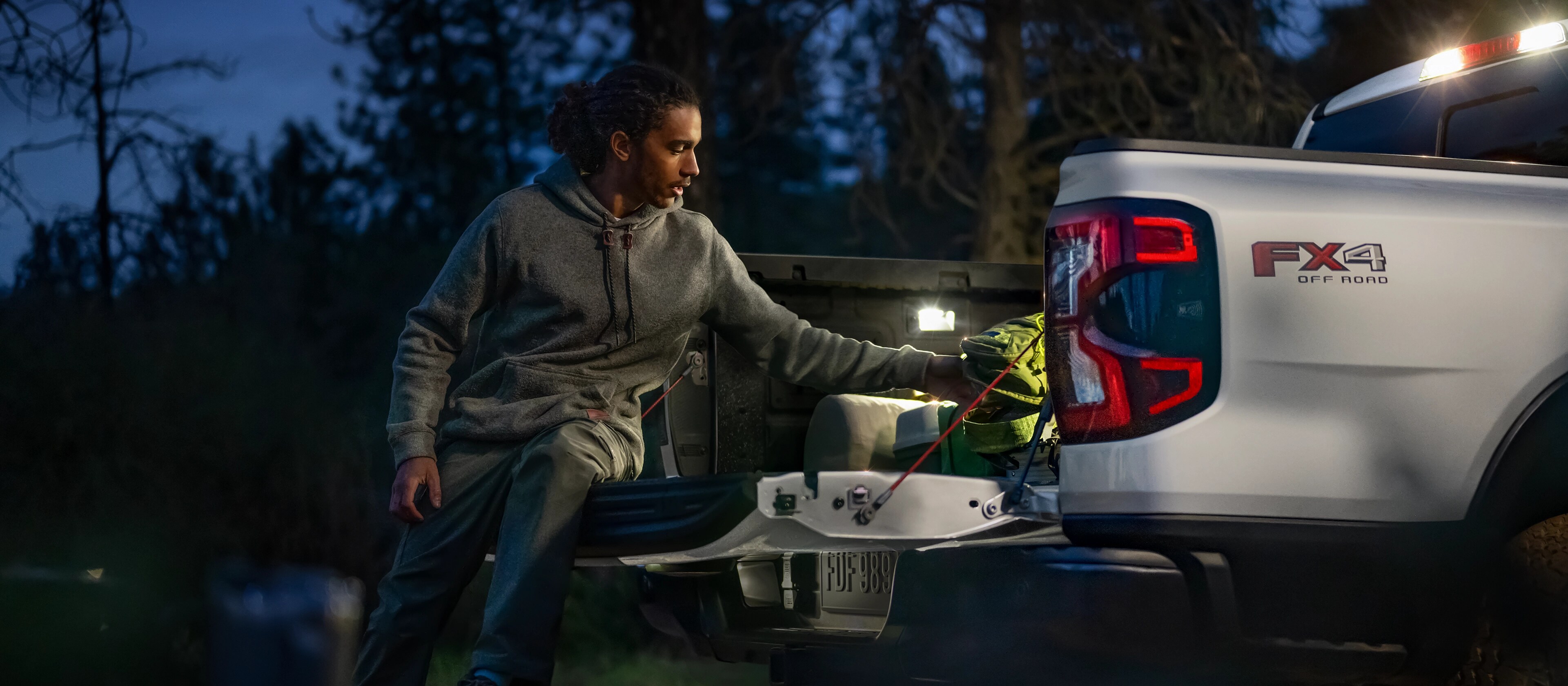 Exterior night shot showcasing LED bed lighting as person unloads gear from a 2025 Ford Ranger®
