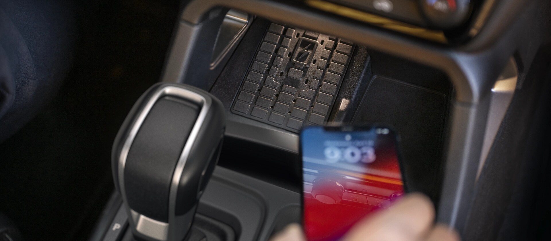 Close-up of a person placing a phone on the wireless charger in the 2025 Ford Ranger®