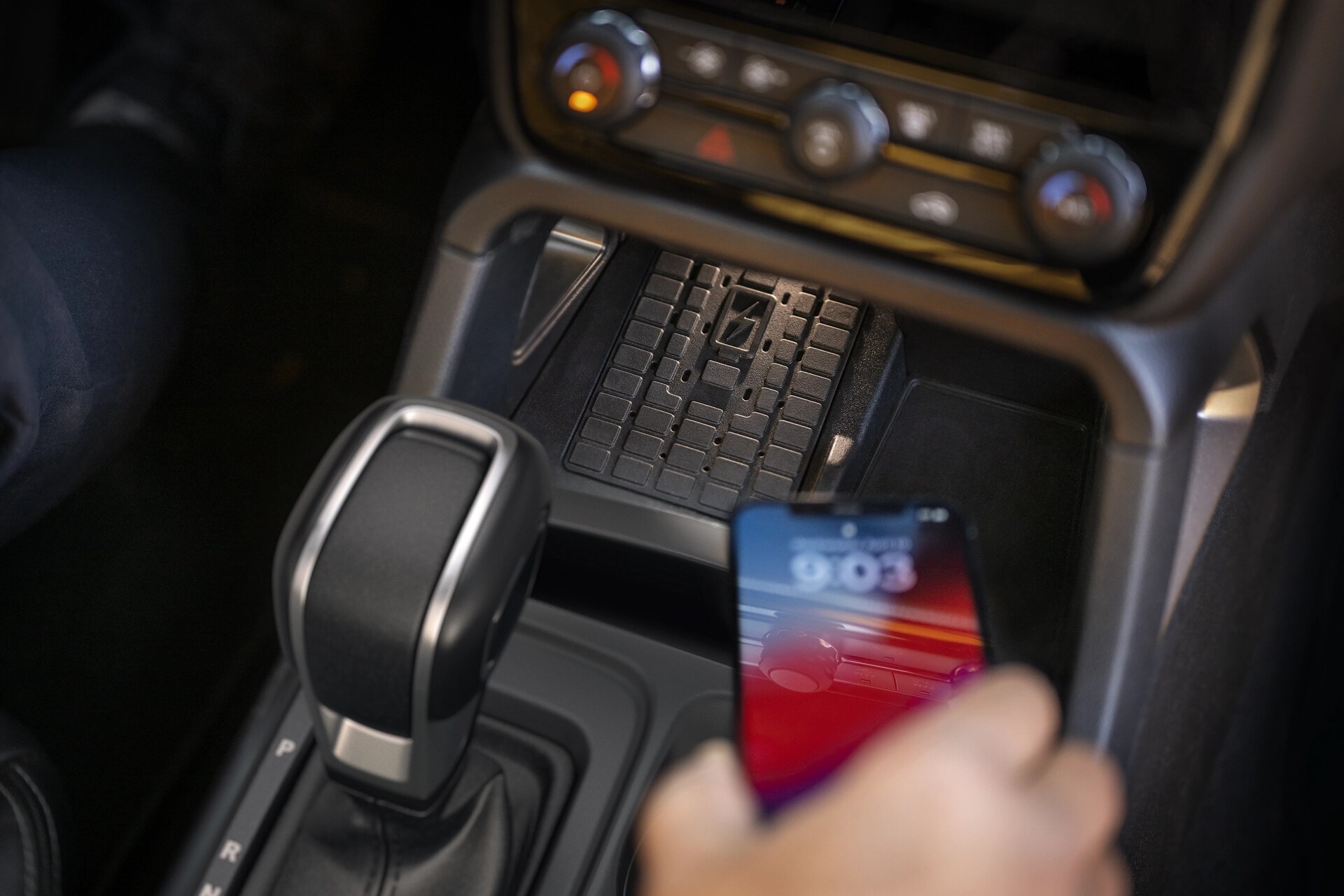 Close-up of a person placing a phone on the wireless charger in the 2025 Ford Ranger®