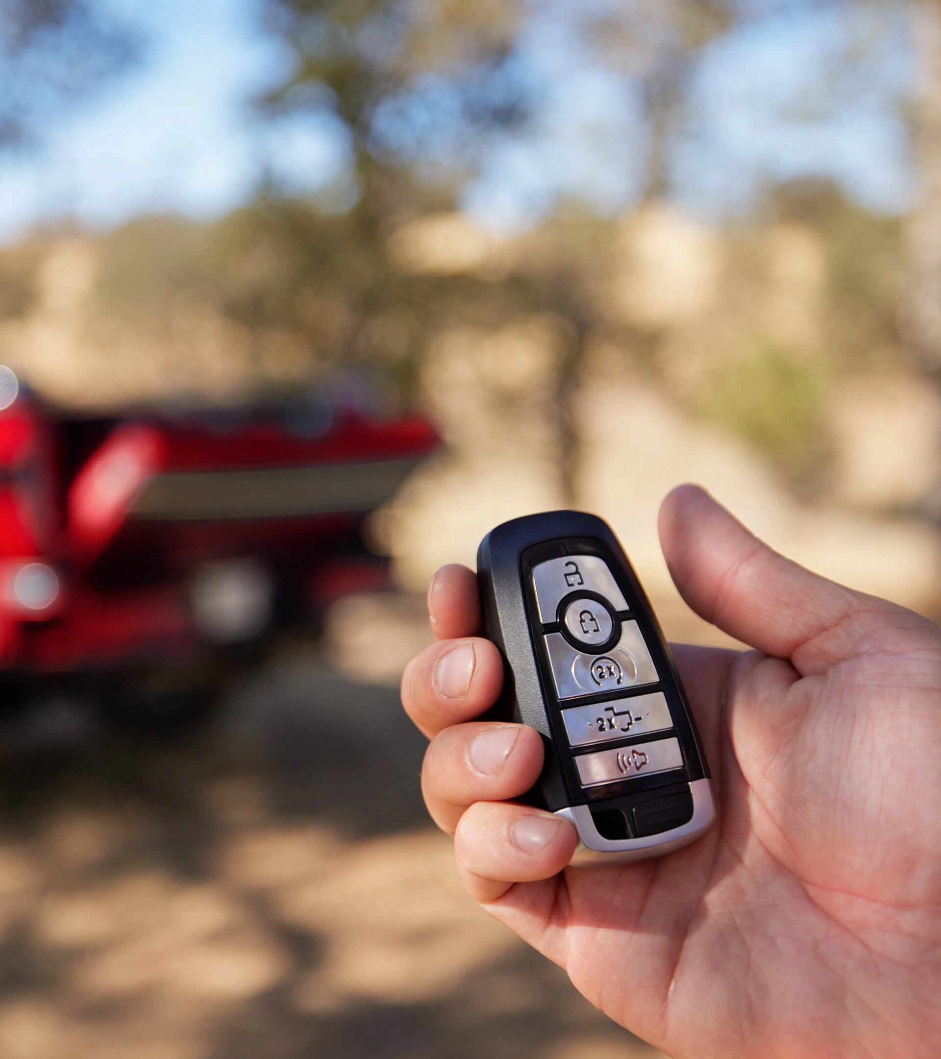 A person's hand clicking the button on their key fob to open the tailgate on their Super Duty® truck