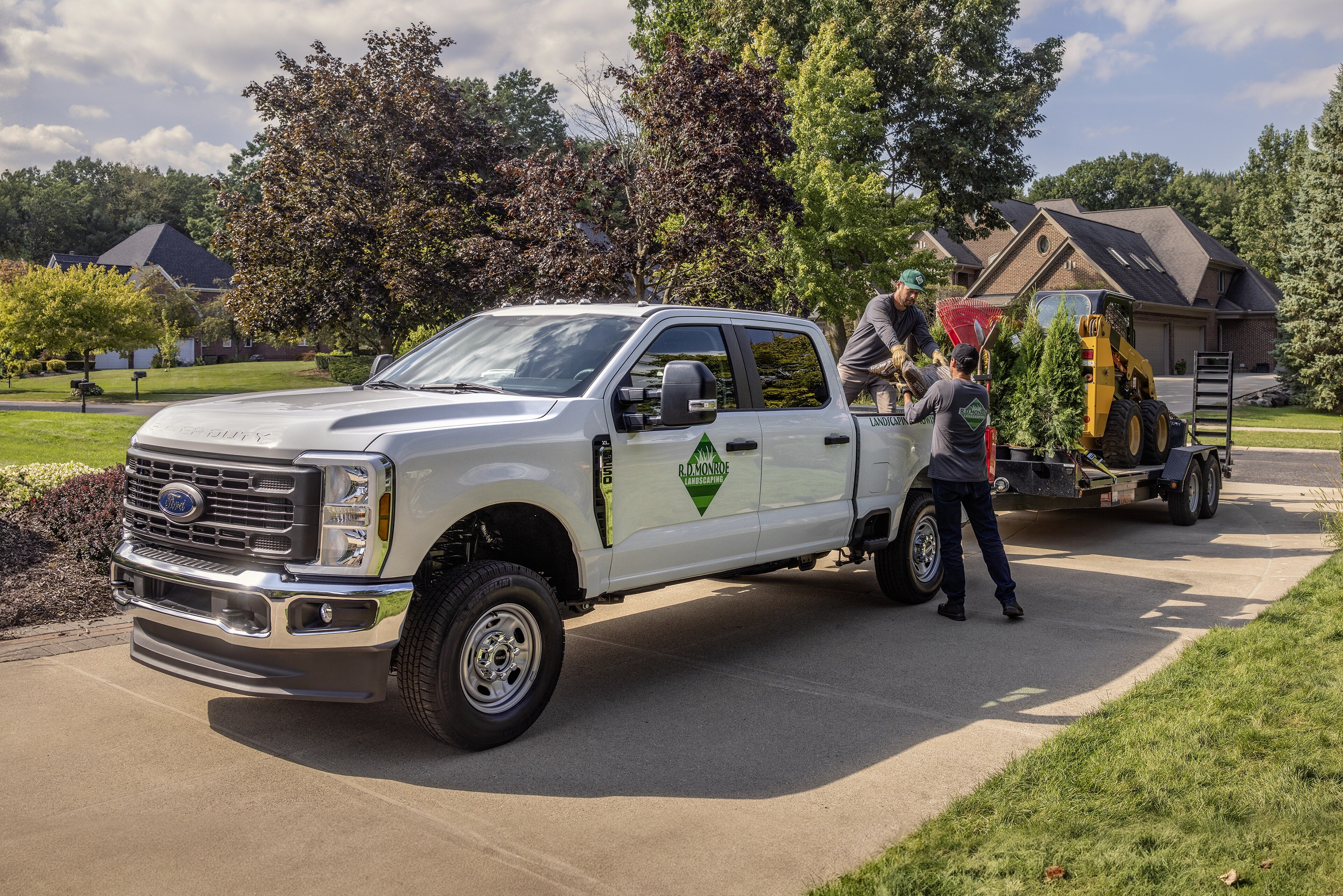 2026 Ford Super Duty® F-350® XL model pulling a large trailer with landscaping equipment into a residential driveway
