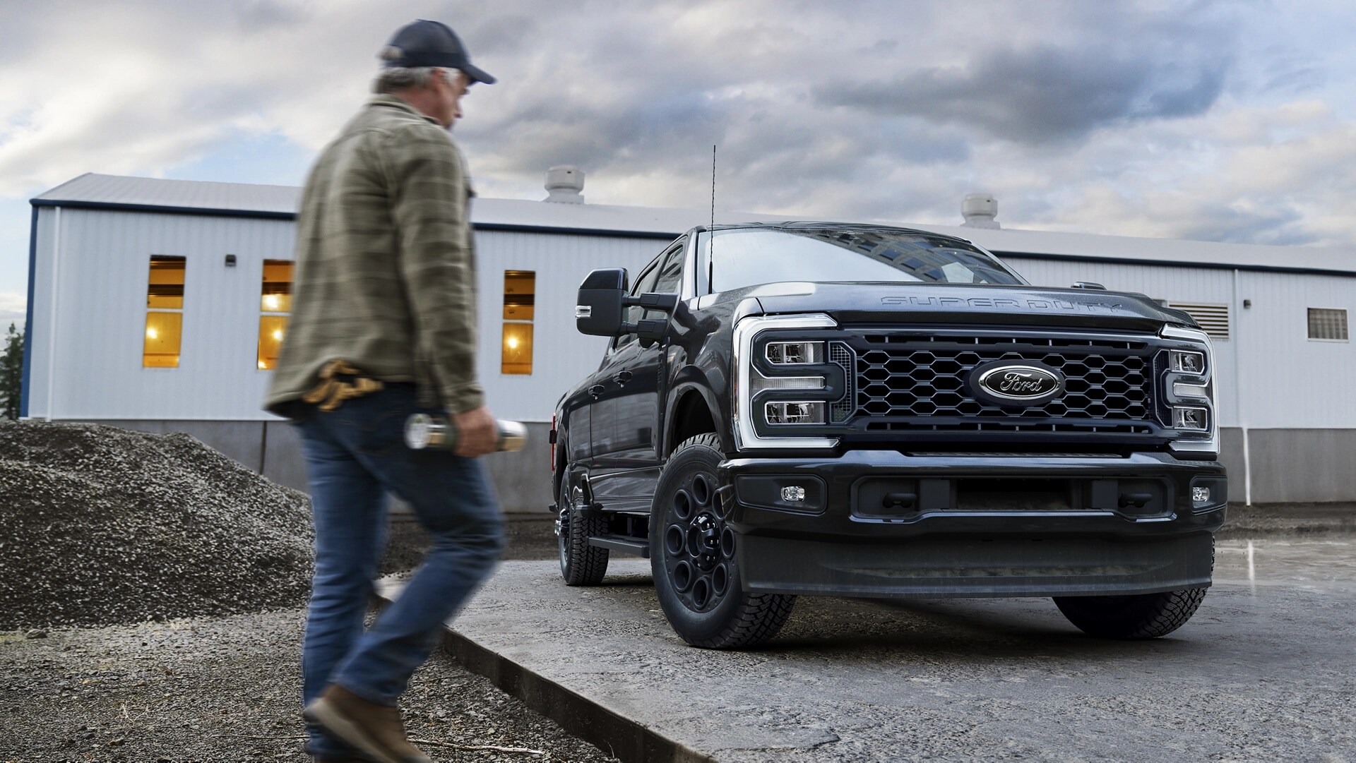 2026 Ford Super Duty® with the Black Appearance Package parked on a cement slab with a person walking toward it